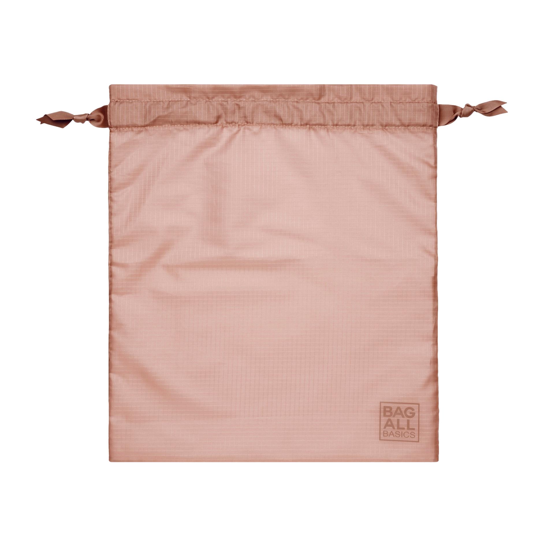 Bag-all Compression Cube in pink blush, featuring drawstring closure and brand logo, part of 8-pack sustainable travel organization set made from recycled nylon material