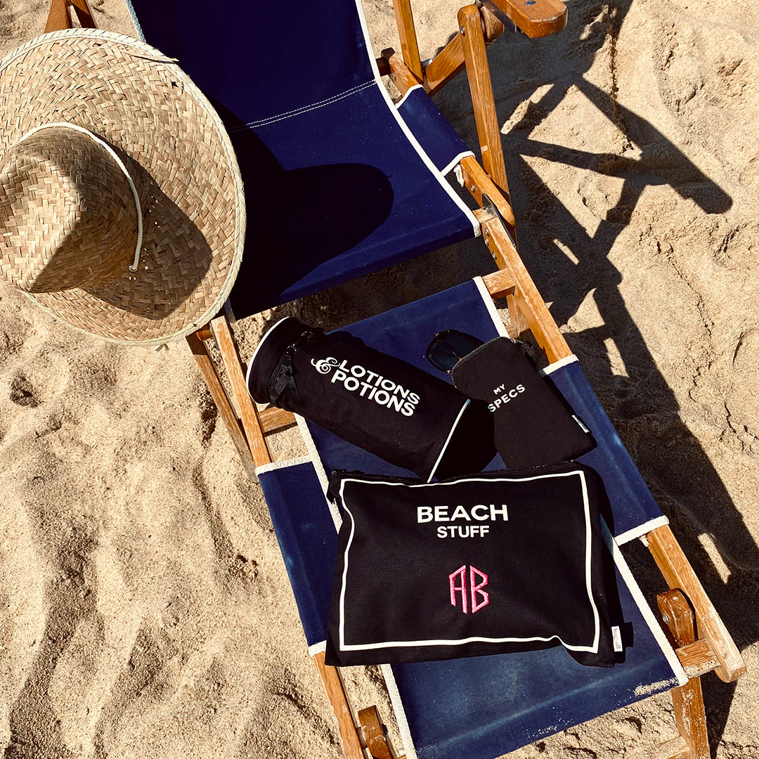 Bag-all Stylish Beach Essential Set in black featuring waterproof pouches on blue beach chair with straw hat, perfect for organizing beach necessities and monogrammable for personalization
