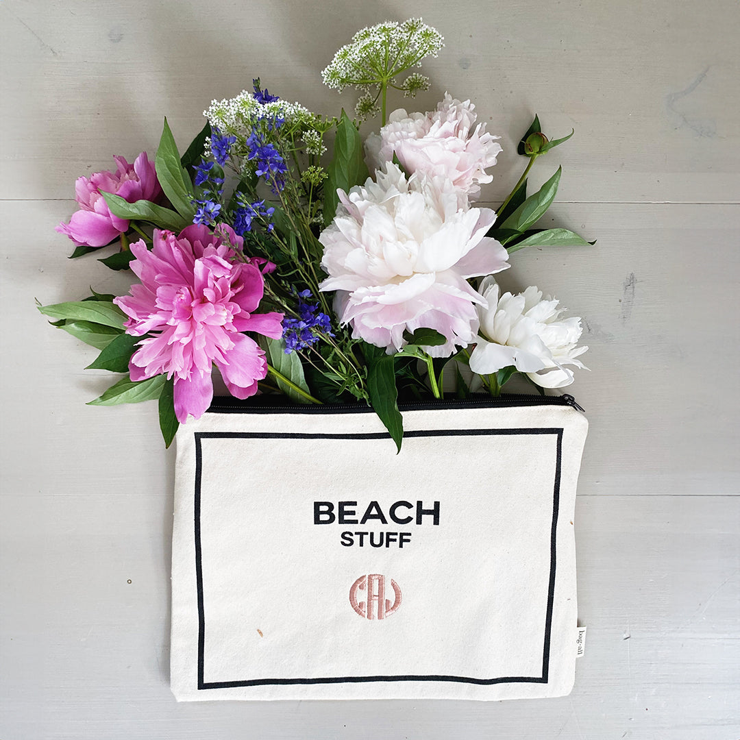 Bag-all Beach Stuff Monogram Pouch with pink and white peonies, blue delphinium, and white Queen Anne's lace arranged in cream cotton organizer with black text