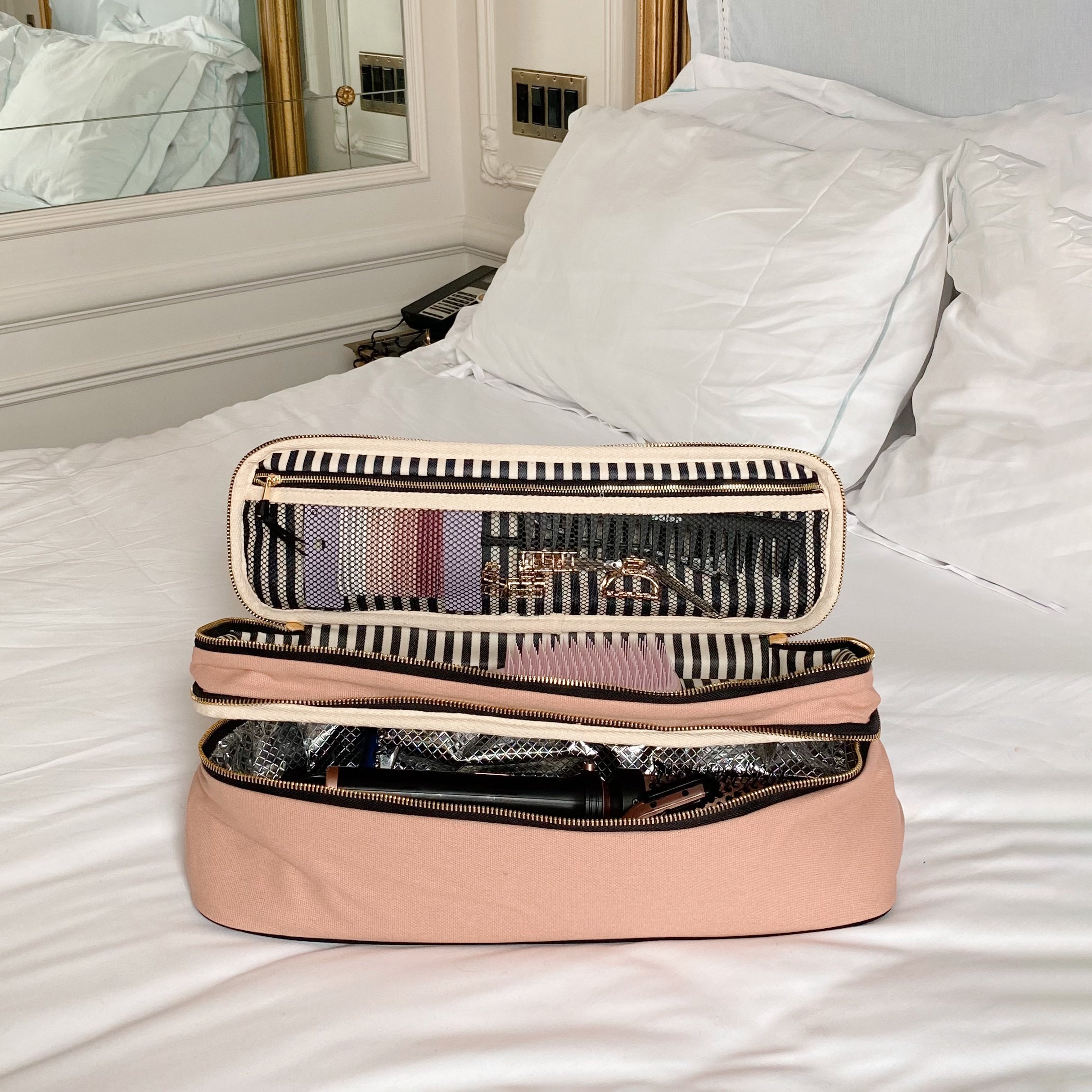 Pink blush Bag-all travel organizers and hair tools set displayed open on a white bed for stylish storage and easy access