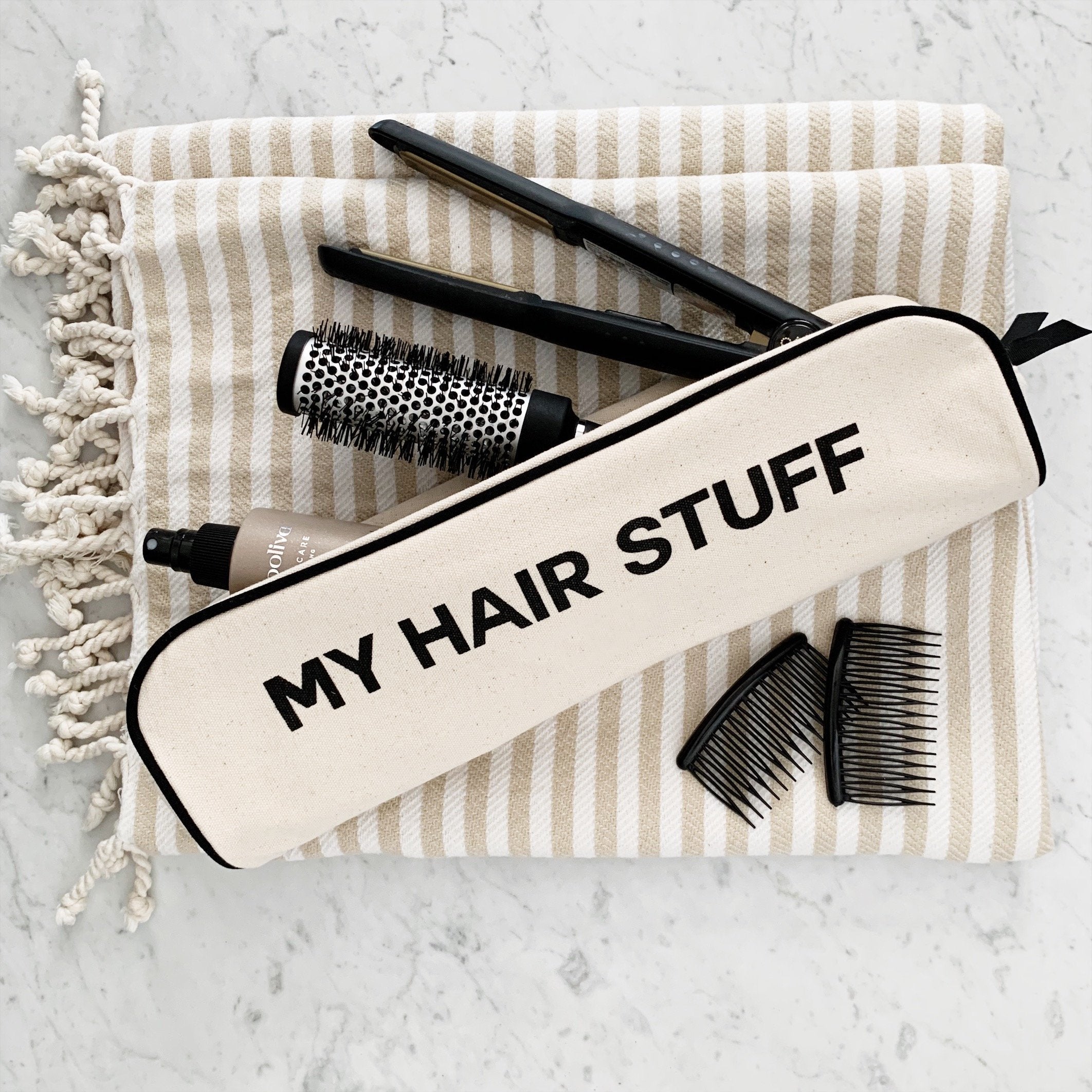 Bag-all cream hair organizer pouch with black zipper and text My Hair Stuff styled with brushes and combs on striped towel
