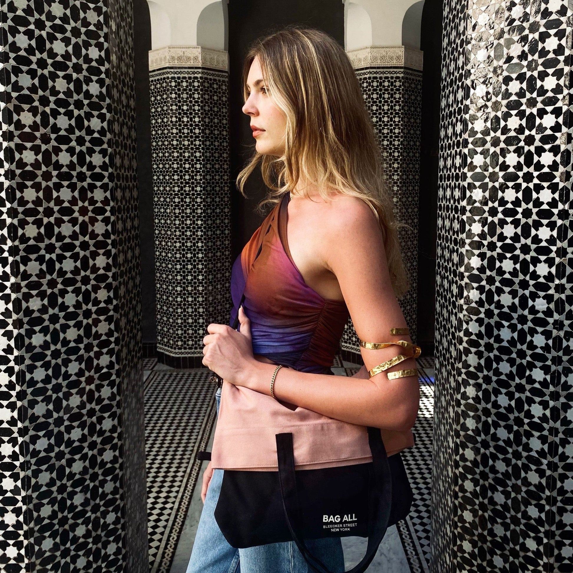 Woman carrying Bag-all 3-Way Tote in Pink/Black, folded as a clutch. Versatile, chic, and perfect for travel