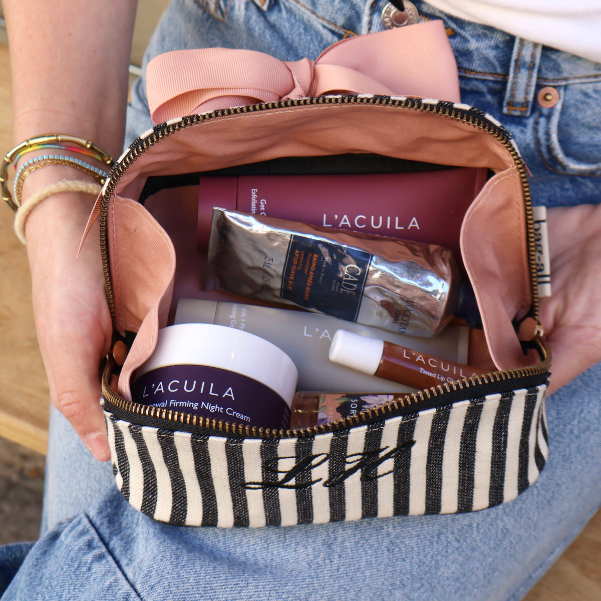 Bag-all striped cotton travel pouch open with skincare items, showing practical organization for frequent travelers