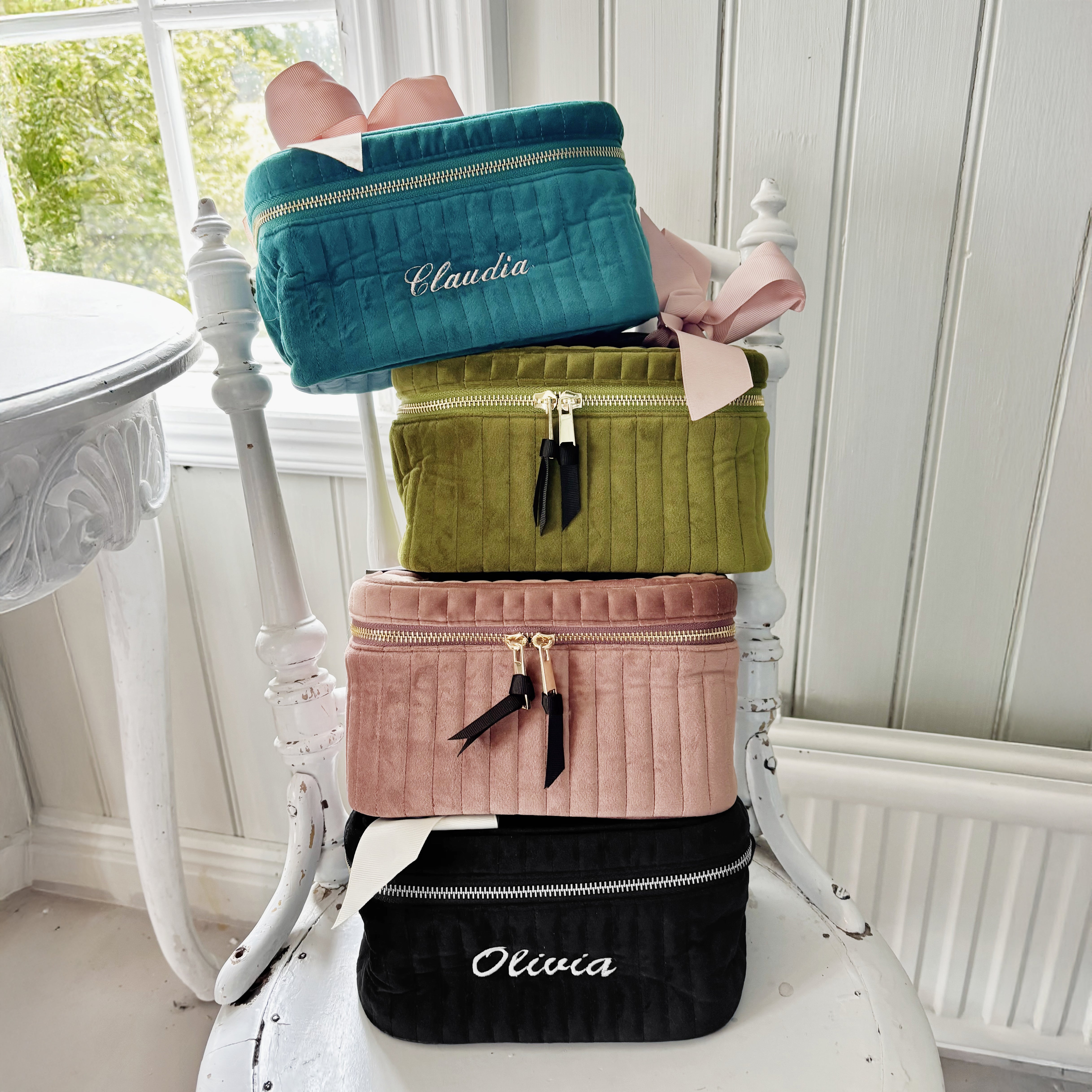 Stacked quilted velvet cosmetic boxes in teal, green, pink, and black with personalized monograms by Bag-all