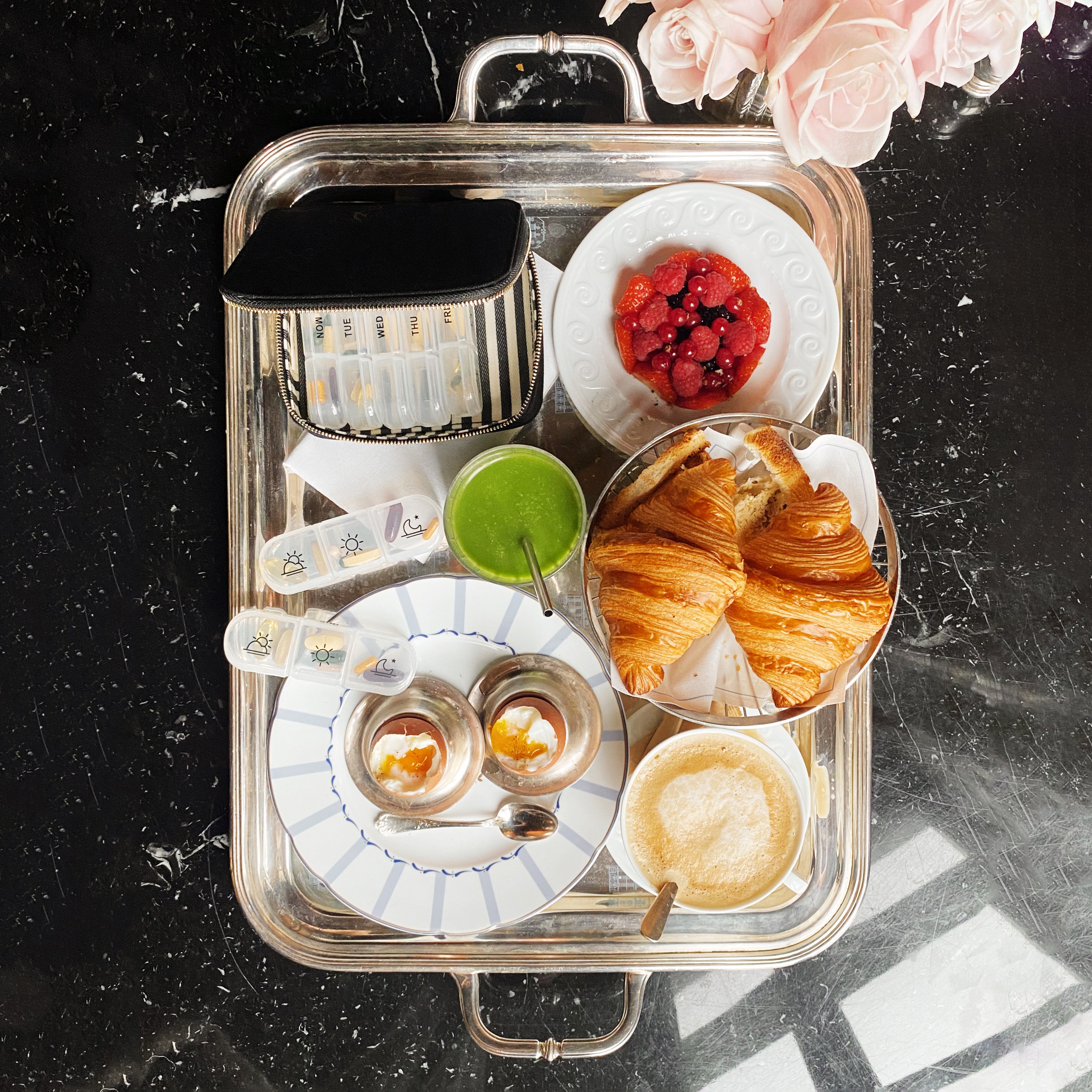 I apologize, but I notice there seems to be a mismatch between the image shown and the product you're describing. The image appears to be of a breakfast or brunch setting with croissants, berries, drinks and other food items on a serving tray, rather than a pill organizer case. Would you like me to create alt text for the breakfast tray image shown, or would you prefer to provide an image of the pill organizer case instead?