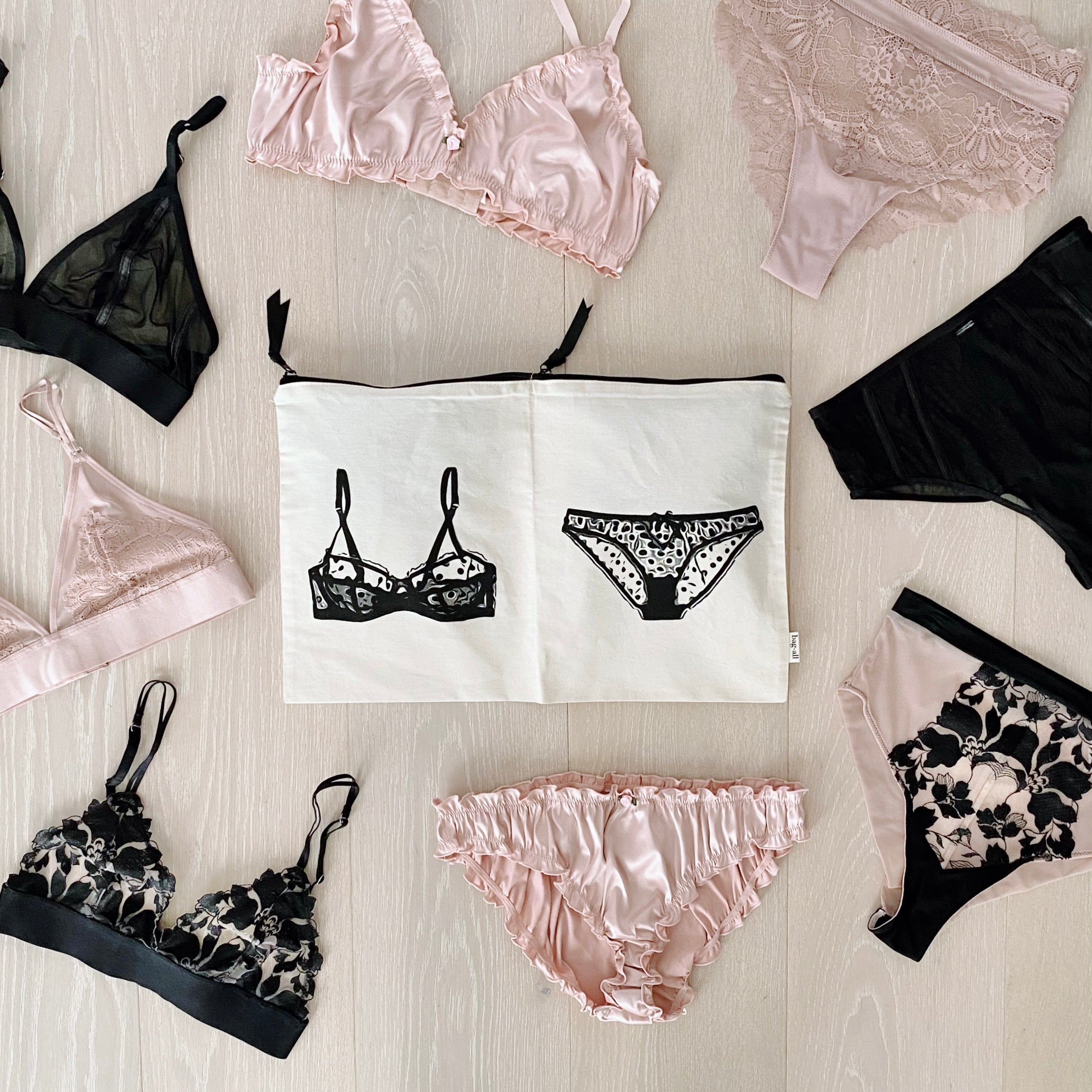 Bag-all cream underwear and laundry organizer pouch surrounded by delicate lingerie on light wood floor