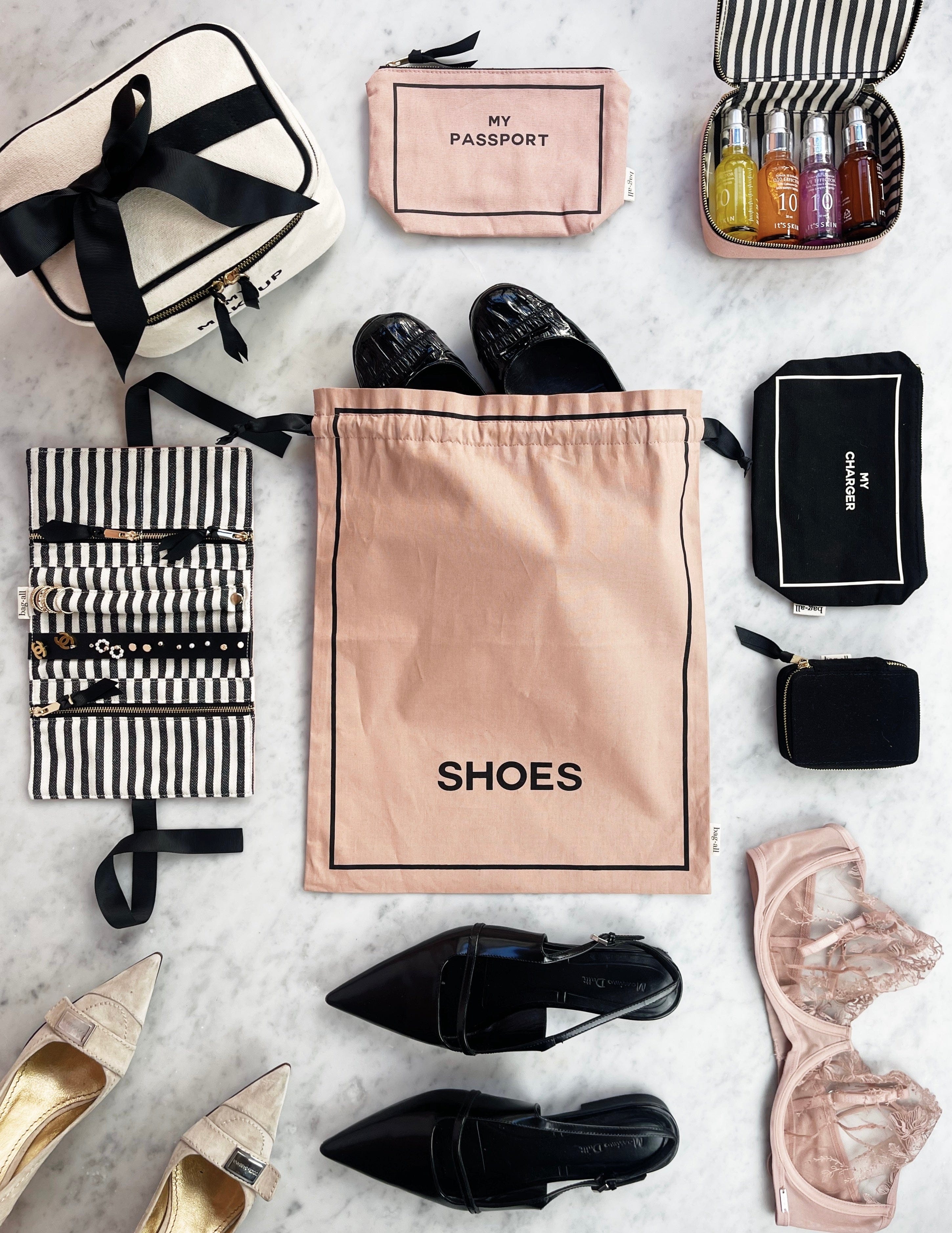 Bag-all Toiletry Travel Gift Set 4-Pack in pink and blush featuring cotton organizer bags for toiletries, shoes, and essentials, with striped pattern and black ribbon accents on marble background