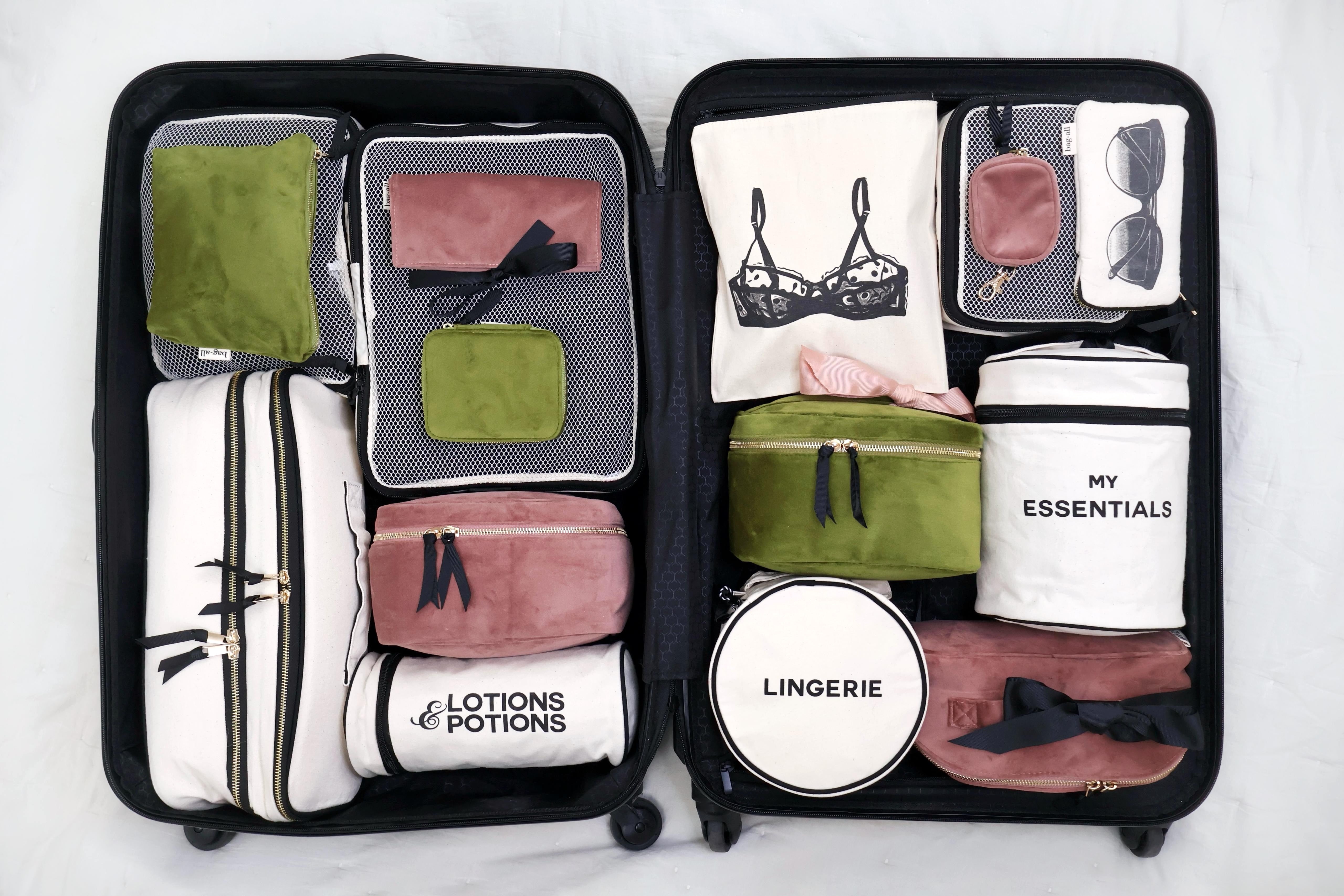 Open suitcase packed with organized Bag-all travel pouches and organizers in muted green, white, and pink tones gallery 1
