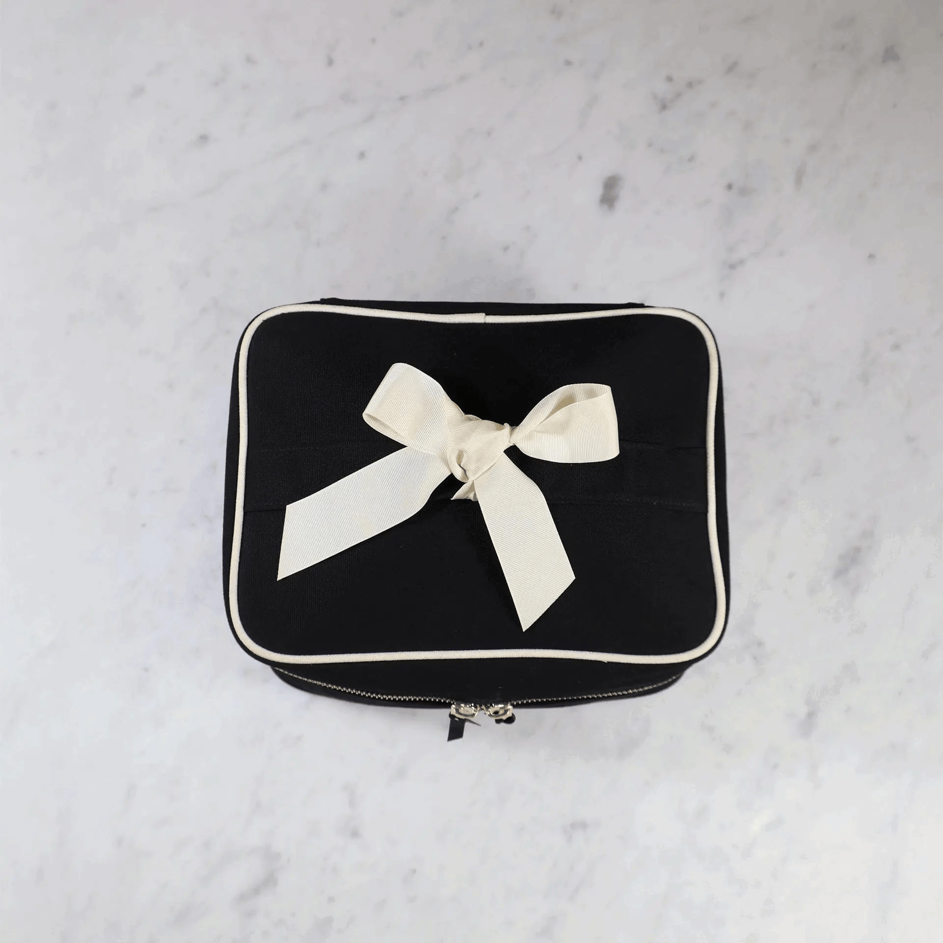 Bag-all large black vanity beauty box with removable insert organizer and white grosgrain ribbon bow on marble surface