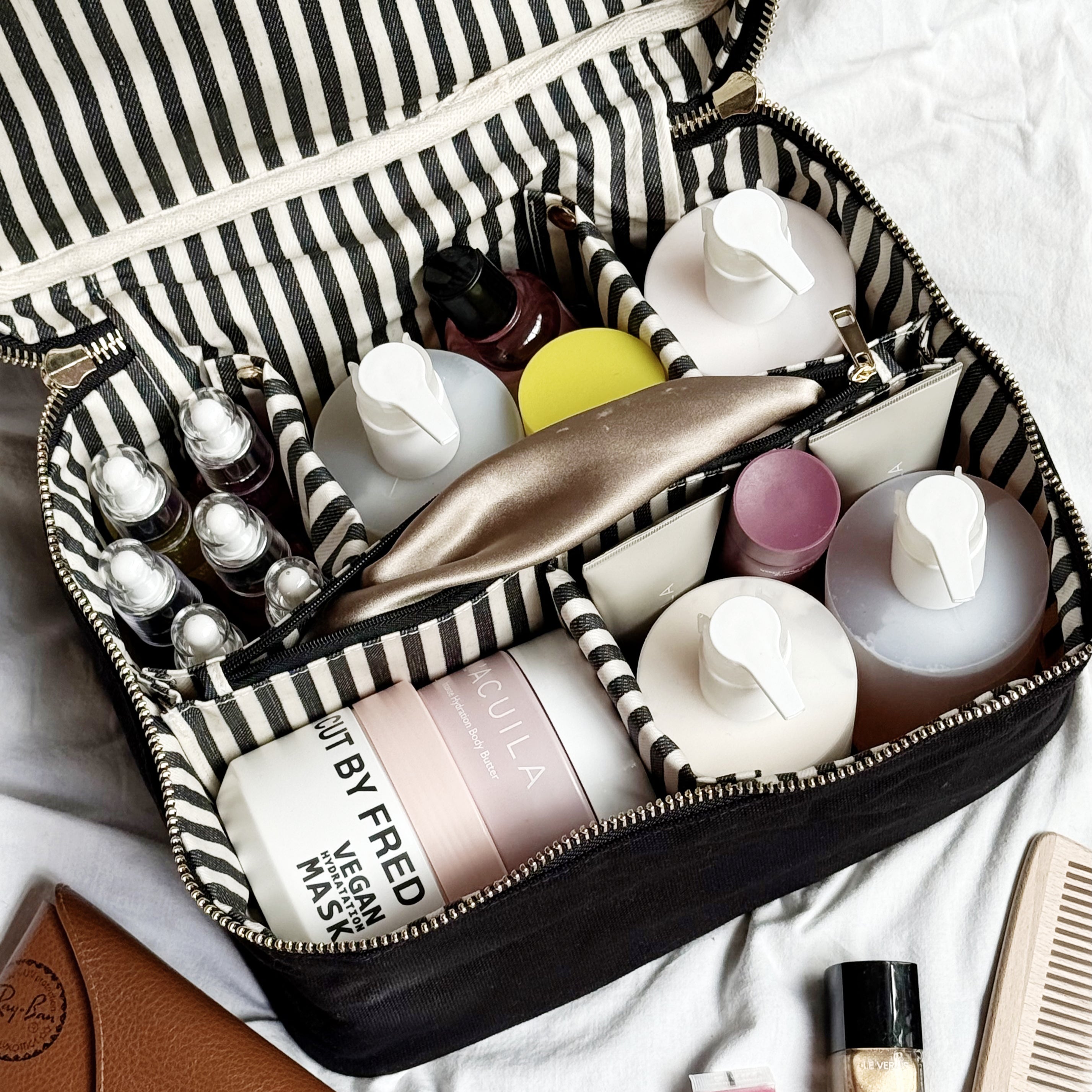 Large black Bag-all vanity beauty box with striped organizer, holding skincare and makeup products neatly inside compartments.