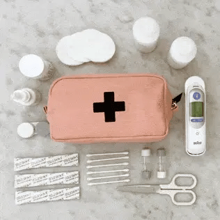 Bag-all First Aid Organizing Pouch in blush pink with medical supplies including bandages, scissors, thermometer, and medicine containers arranged on gray surface