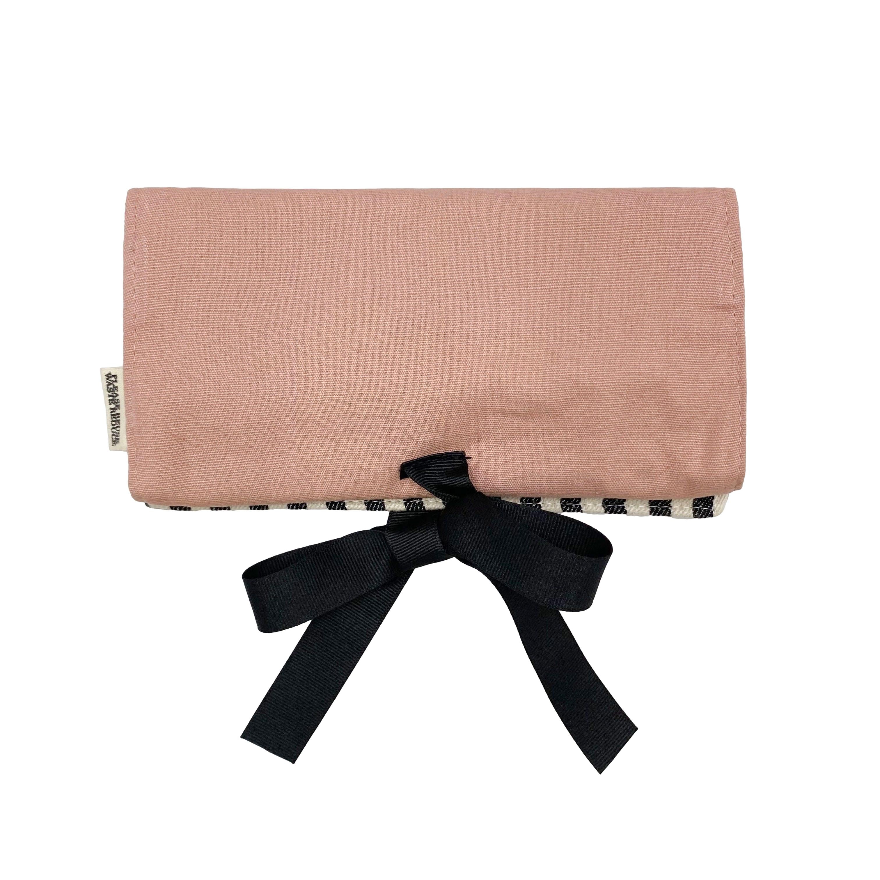 Bag-all Jewelry Organizer Travel Pouch in blush pink with black bow, featuring striped interior, multiple compartments, leather earring holder and ring storage, perfect for travel and home organization
