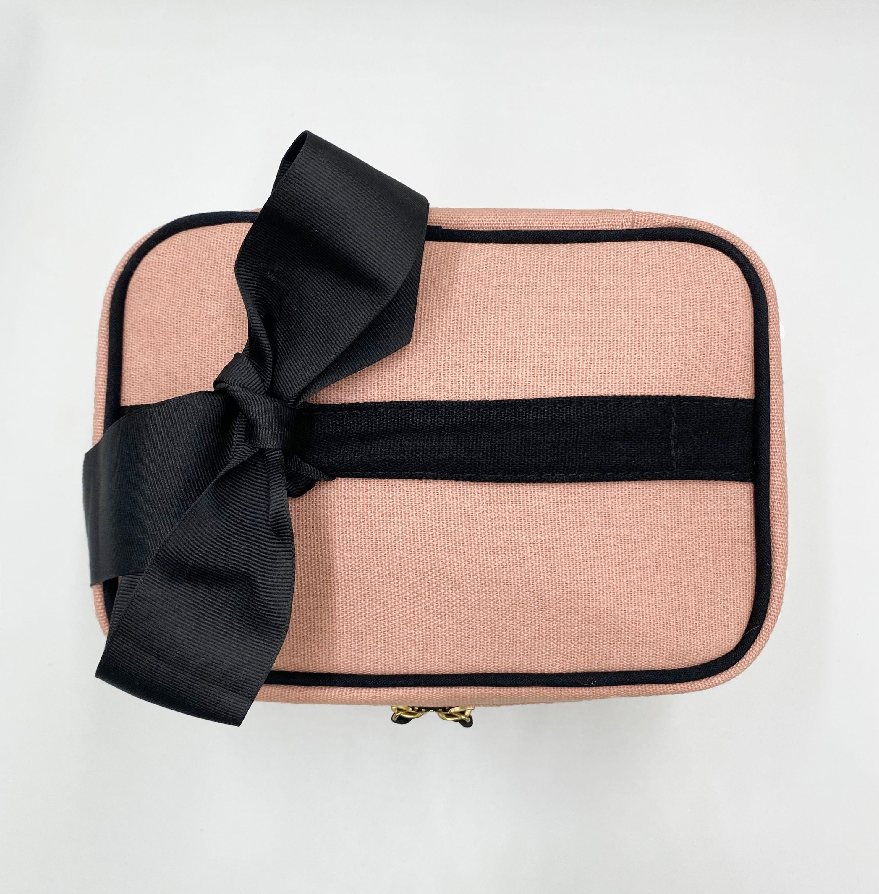 Bag-all My Makeup Cosmetic Box in blush pink with black ribbon bow, piping, and gold zipper - stylish beauty organizer with laminated interior and handle for portable storage