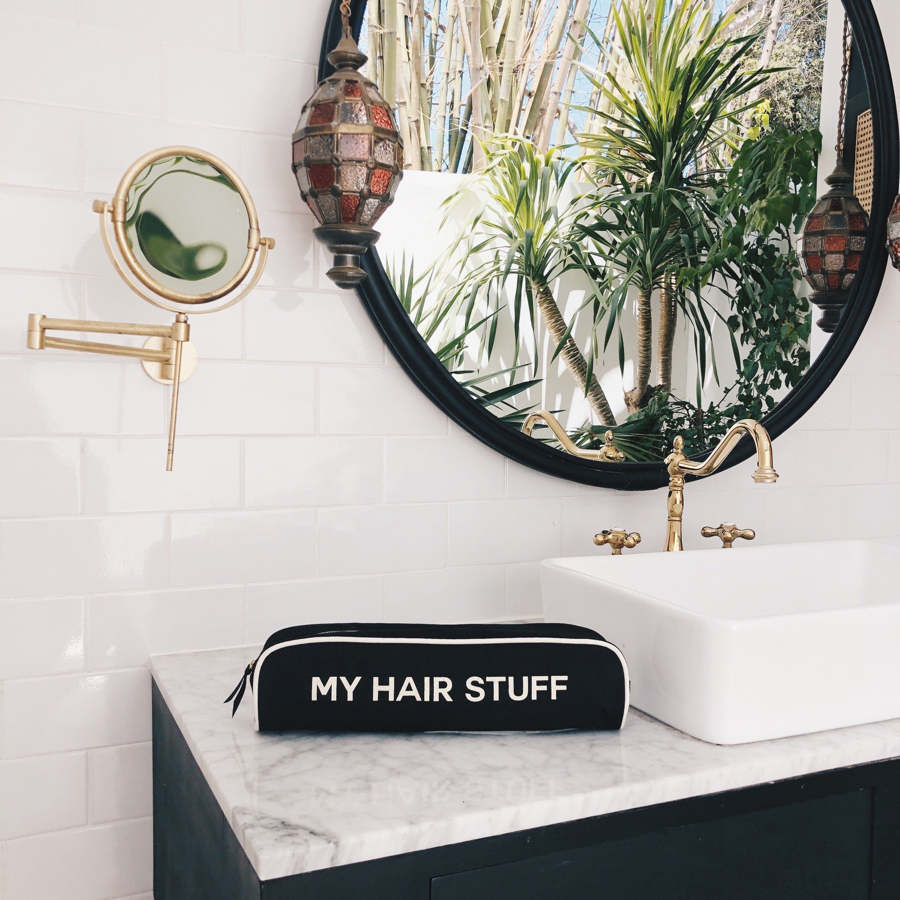 Bag-all Hair Stuff Travel Case in black displayed on marble bathroom counter, featuring stylish organization for heat styling tools and accessories against modern decor with round mirror