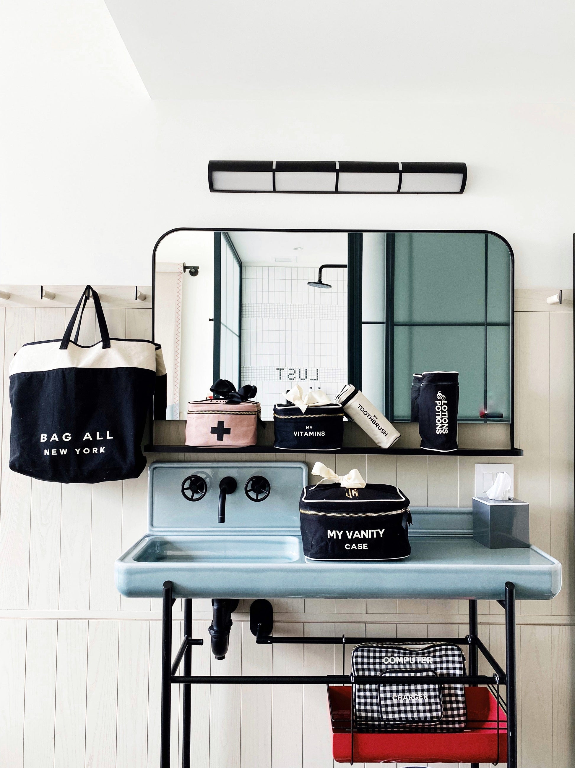 Bag-all Pink First Aid Storage Box with black cross print and bow, shown with other organizing cases on vintage-style bathroom vanity, featuring eco-friendly cotton material