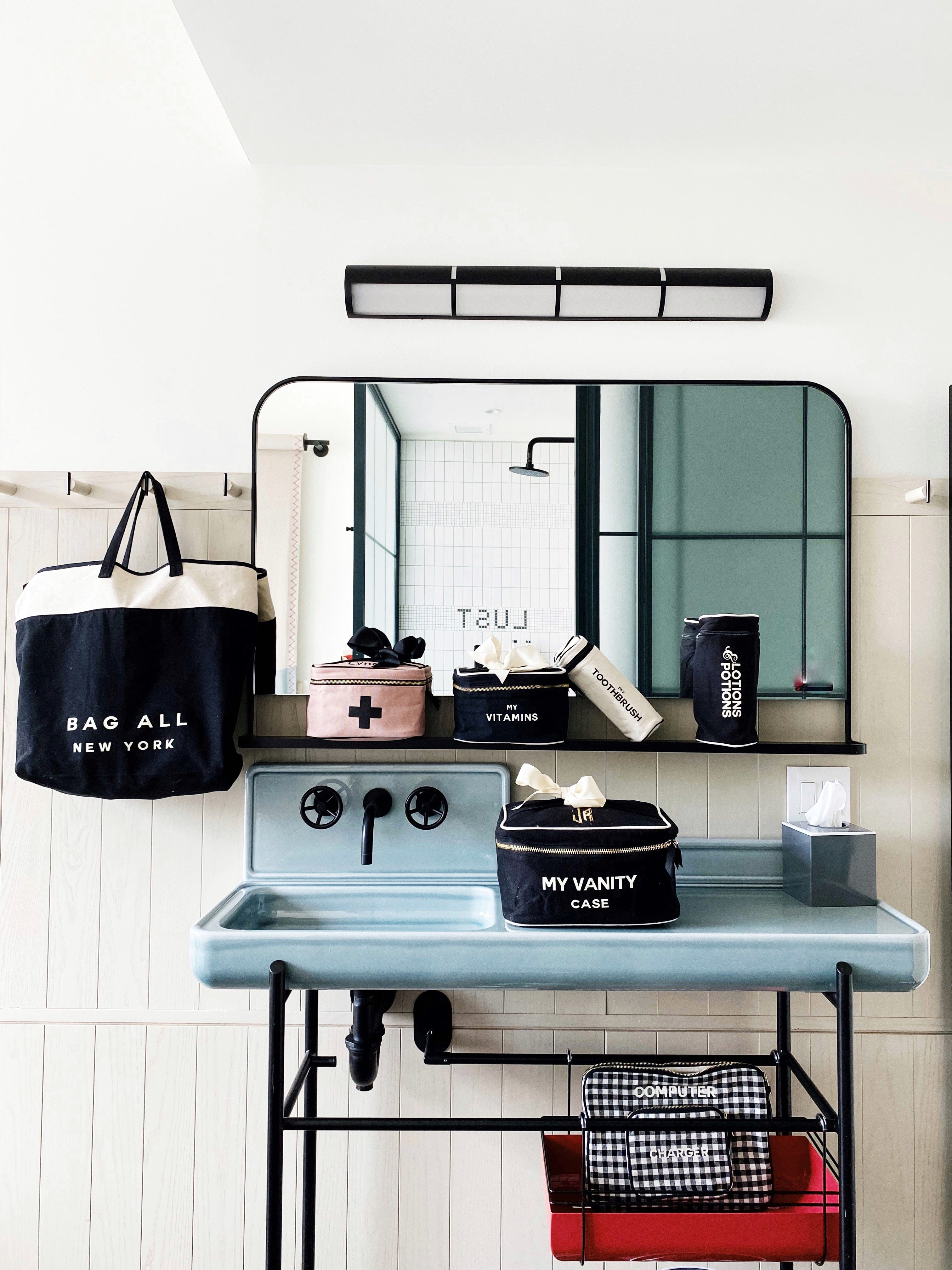Bag-all Pink First Aid Storage Box with black cross print and bow, shown with other organizing cases on vintage-style bathroom vanity, featuring eco-friendly cotton material