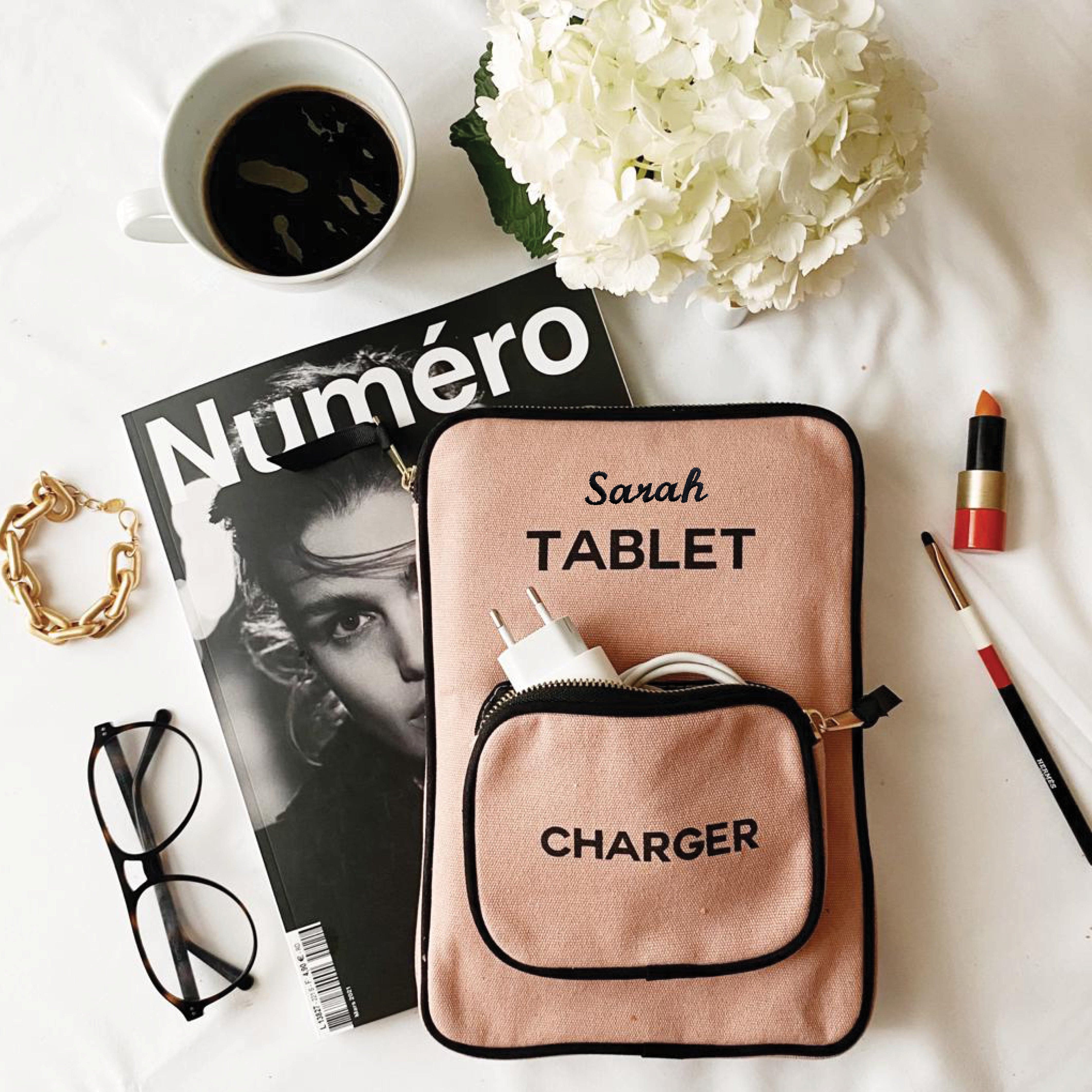 Bag-all pink tablet case with charger pocket styled with fashion magazine, coffee cup, white hydrangea, lipstick and reading glasses on white surface, showcasing modern organization