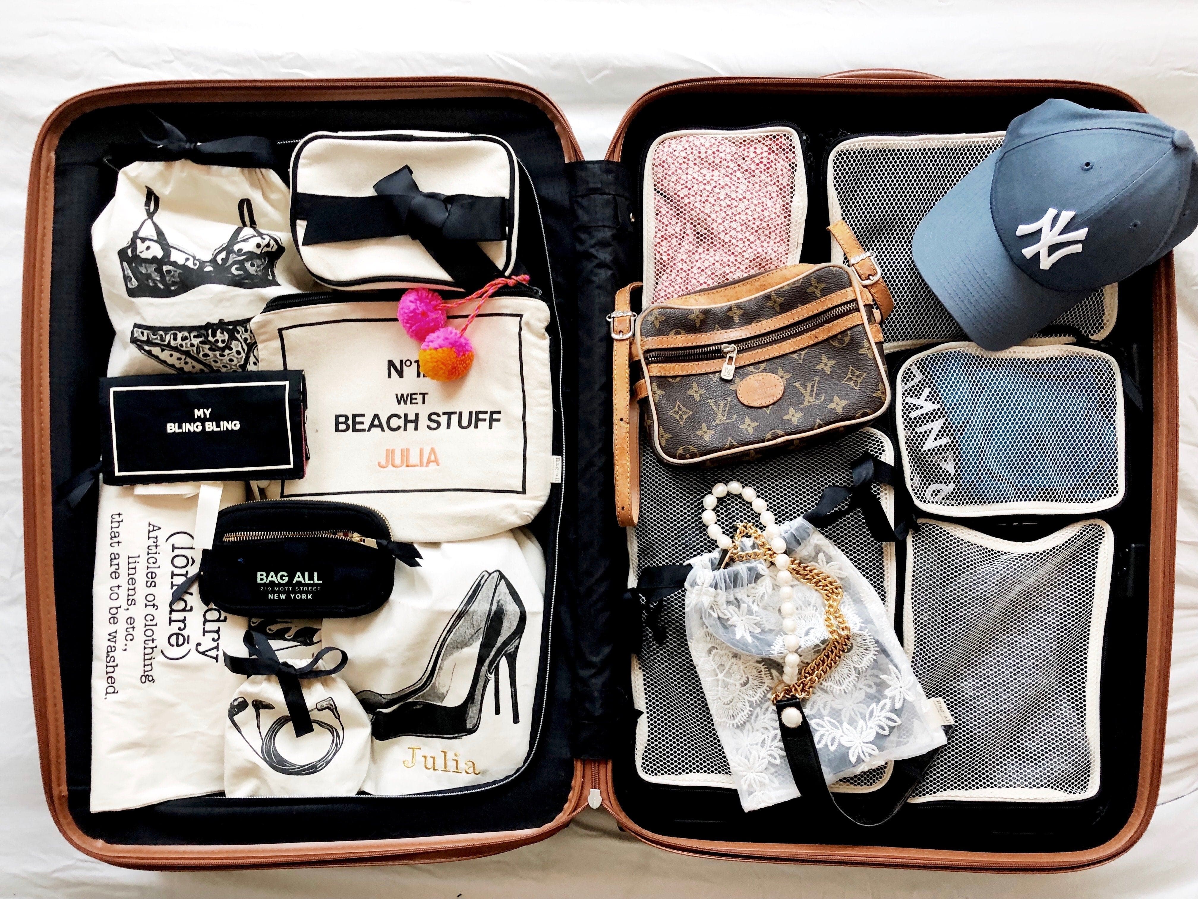 Bag-all Cotton Packing Cubes in black shown organizing travel items in open suitcase, featuring mesh compartments with various clothing, accessories, and beach essentials neatly arranged