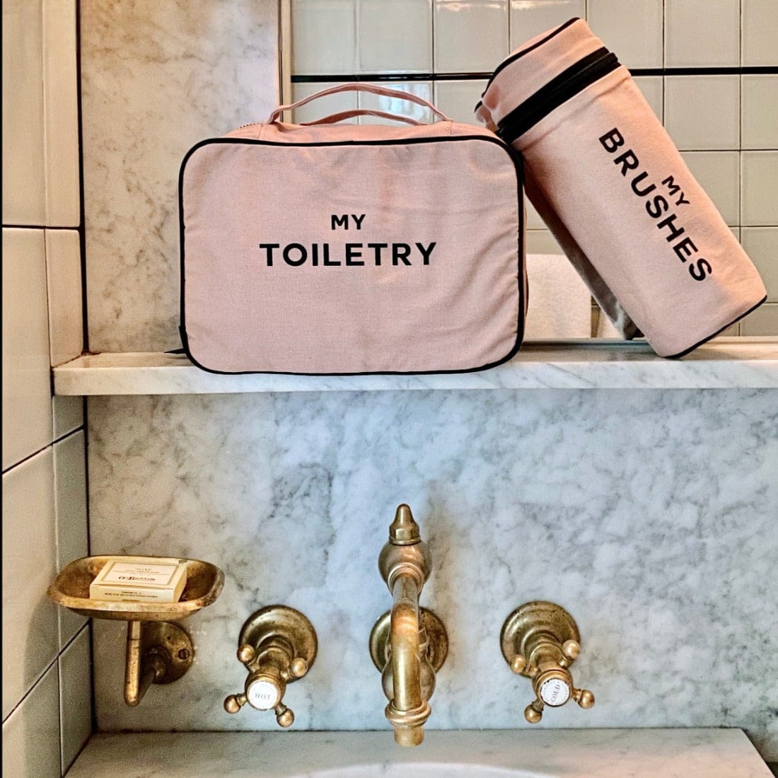 Bag-all pink cylinder Brushes case and Toiletry organizer displayed on marble bathroom shelf with vintage brass fixtures, perfect for beauty tool storage