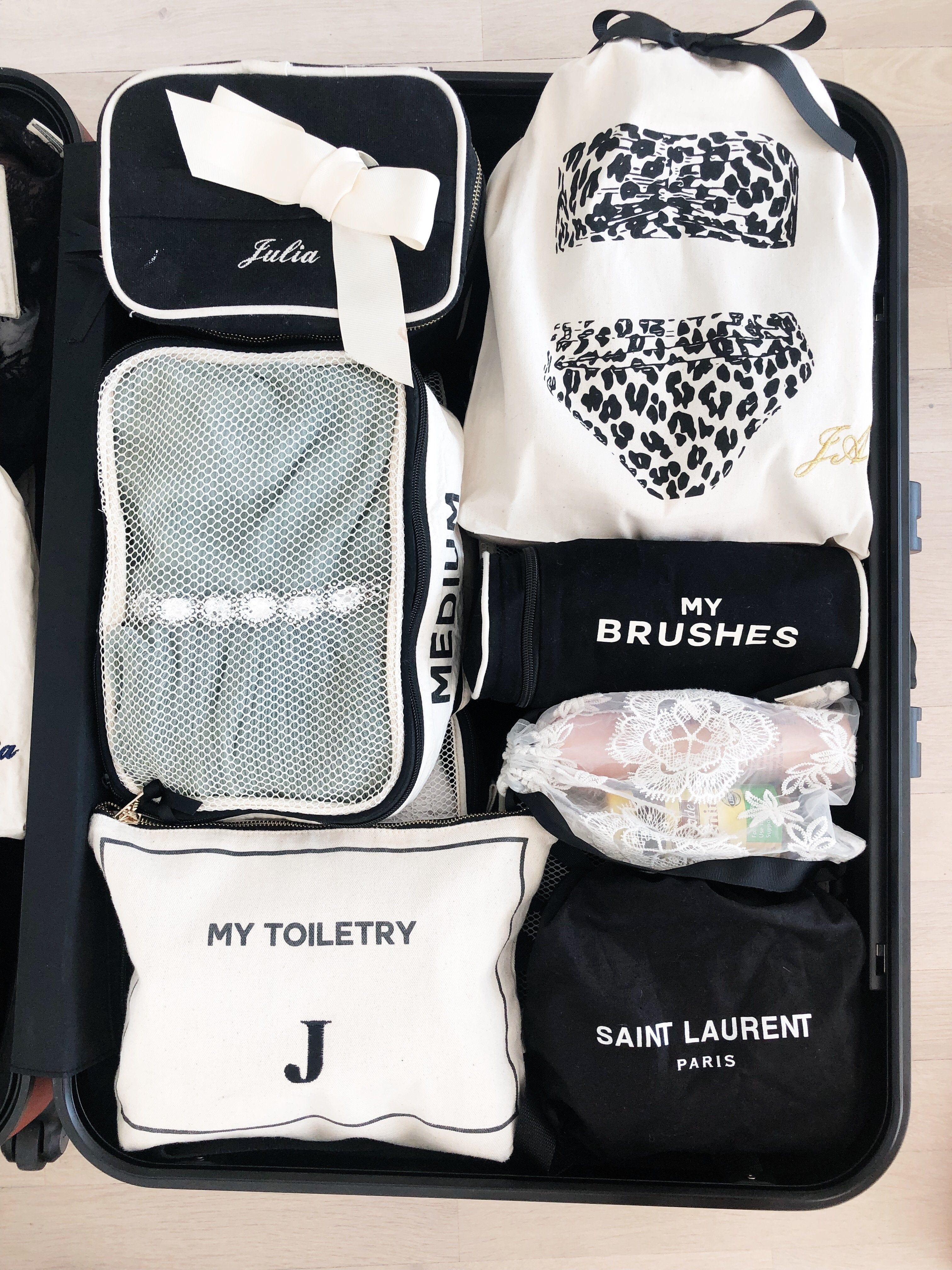 Bag-all Toiletry Pouch with Coated Lining in cream color, featuring organized compartments and leak-proof design, shown in an open suitcase with other travel organizers and pouches