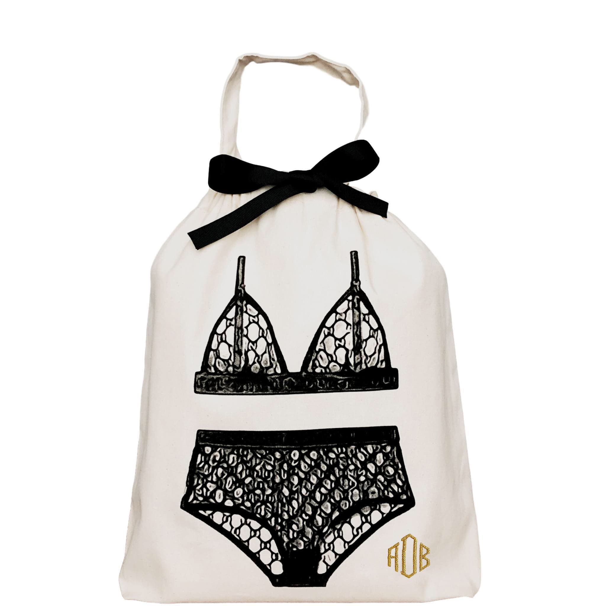 Bag-all London Lingerie Travel Bag in cream cotton with black lace lingerie illustration and decorative bow, featuring monogram detail and drawstring closure