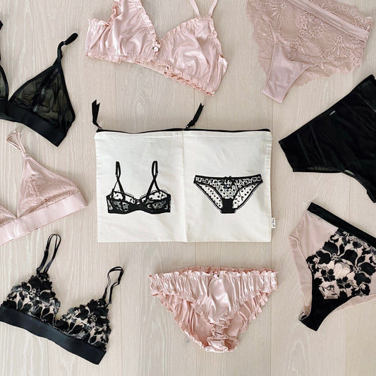 Bag-all Double Lingerie Packing Pouch in Cream with illustrated bra and panty design, surrounded by pink and black lingerie sets on light wooden surface