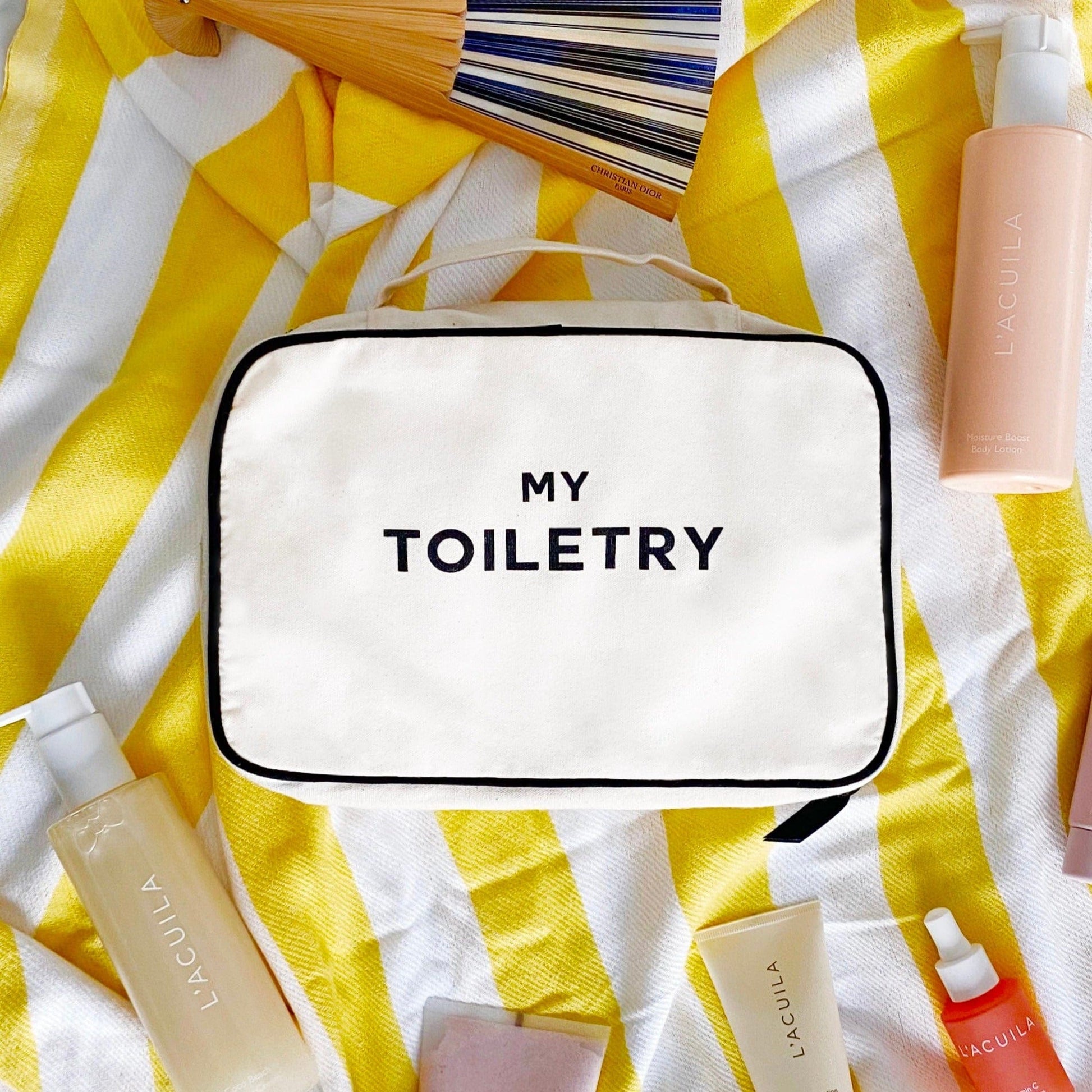 Bag-all Folding/Hanging Toiletry Case in cream on yellow striped background with beauty products, featuring 'MY TOILETRY' text and multiple compartments for organized travel storage