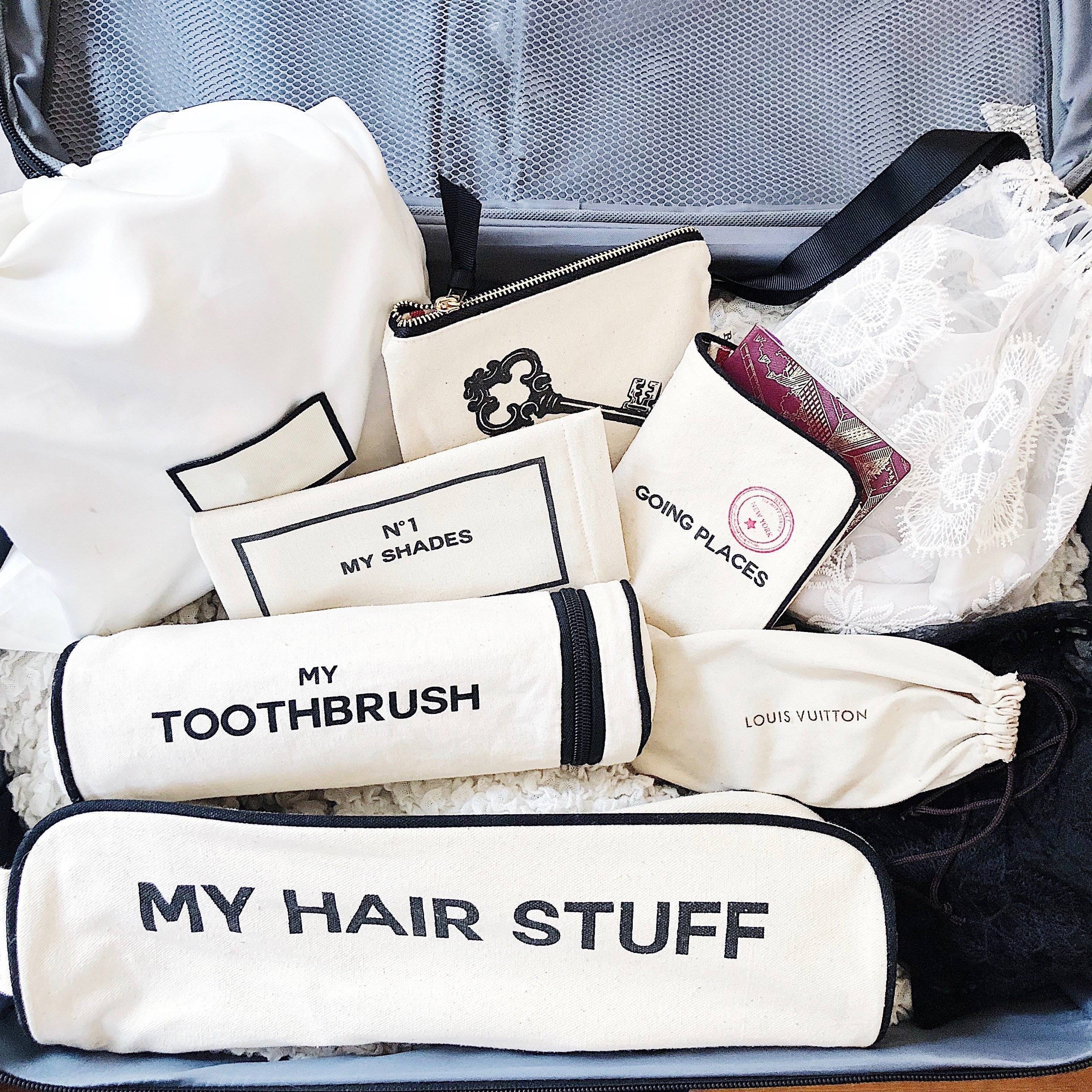 Bag-all Hair Stuff Travel Case in cream with matching organizer bags for toiletries and accessories, featuring black text labels and zipper closures, displayed in suitcase