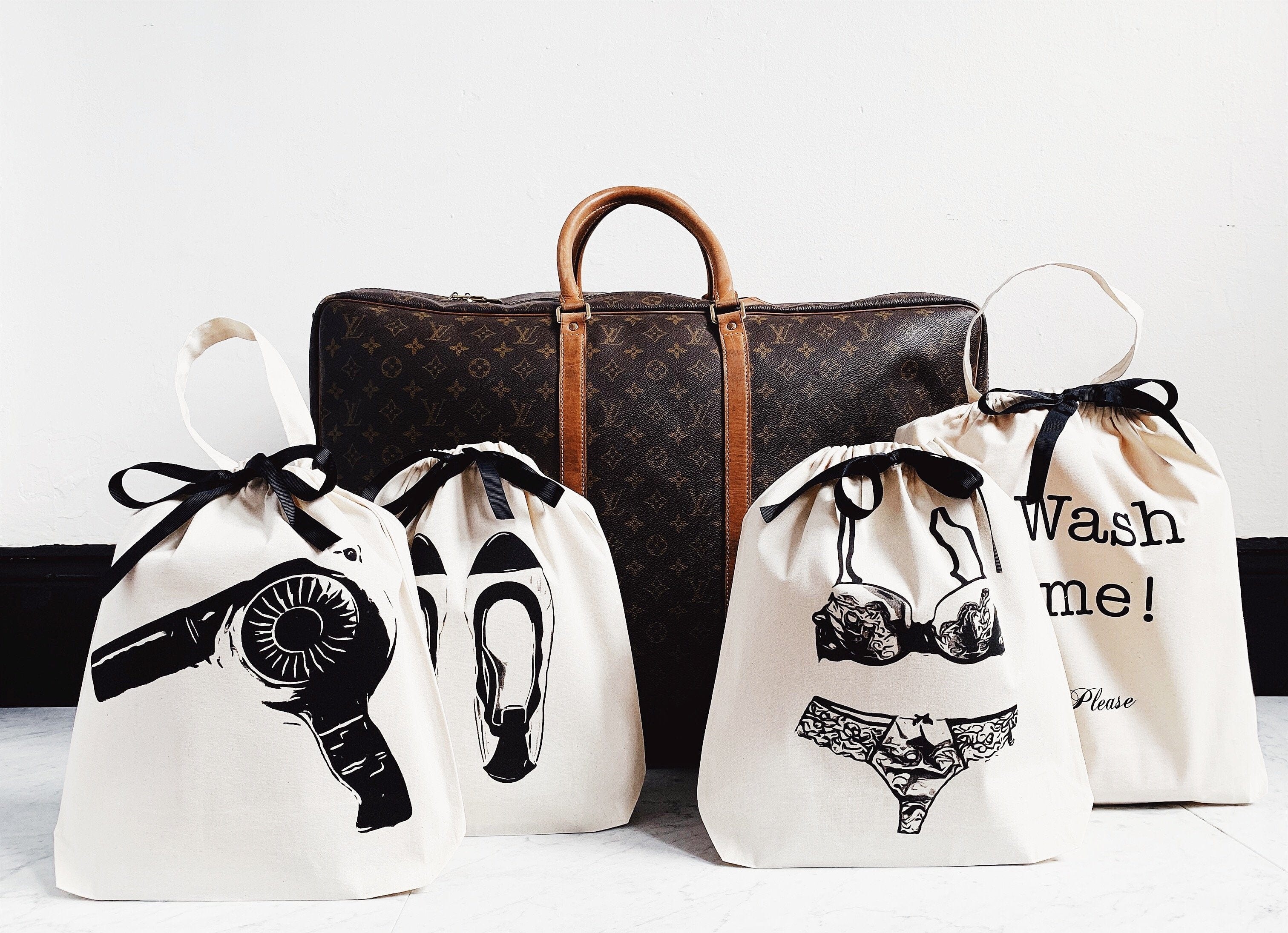 Bag-all Cream Hair Dryer Travel Bag with illustrated drawstring organizers for hairdryer, shoes, lingerie and laundry, featuring black printed icons and text on white cotton canvas