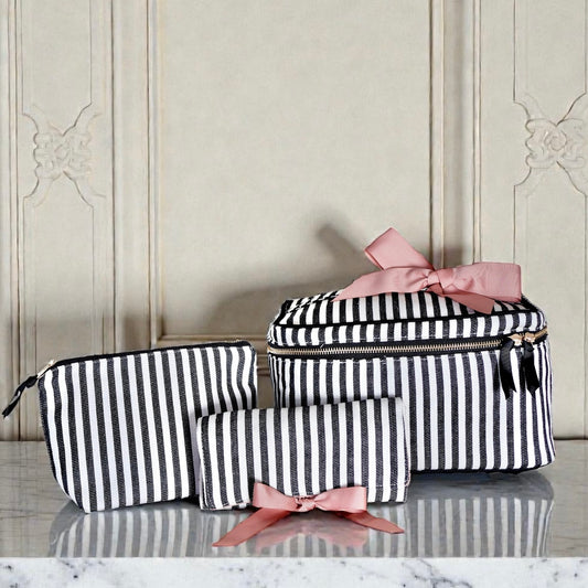 Set of three black and white striped Bag-all travel, jewelry, and makeup organizers with pink ribbon bows on marble surface