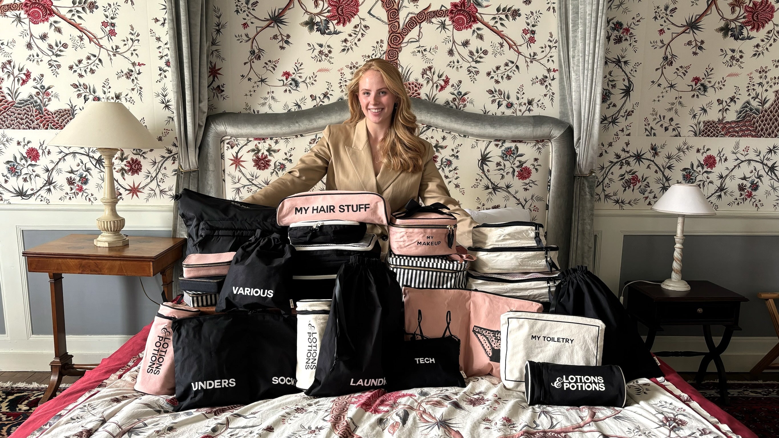 Woman seated on ornate bed surrounded by neatly organized Bag-all pouches and travel bags gallery position 1