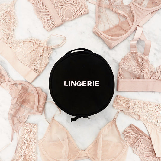 Black Round Lingerie Case by Bag-all surrounded by delicate nude lace bras and panties on white background