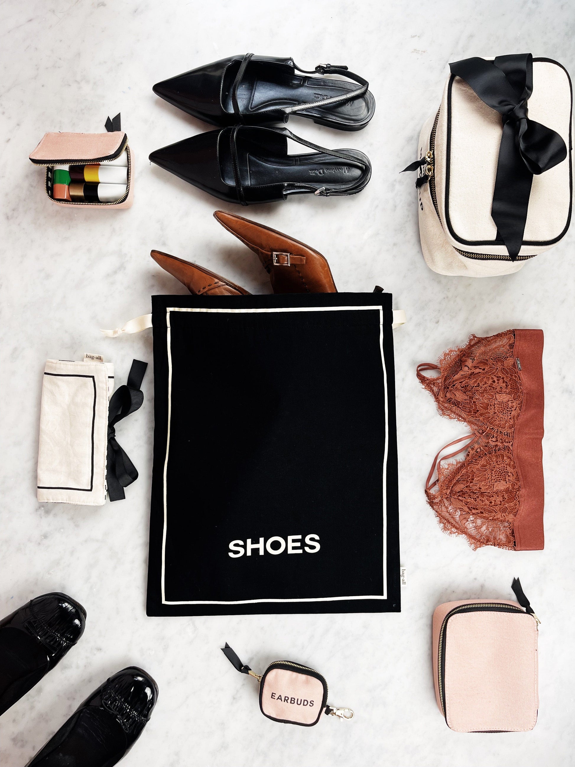 Bag-all Toiletry Travel Gift Set Deal 4-Pack featuring black cotton shoe bag, toiletry pouch, and organizing bags with leather shoes and travel accessories on marble surface