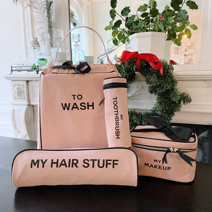 Bag-all pink travel set with To Wash laundry bag, My Hair Stuff pouch, My Toothbrush case, and My Makeup bag on table