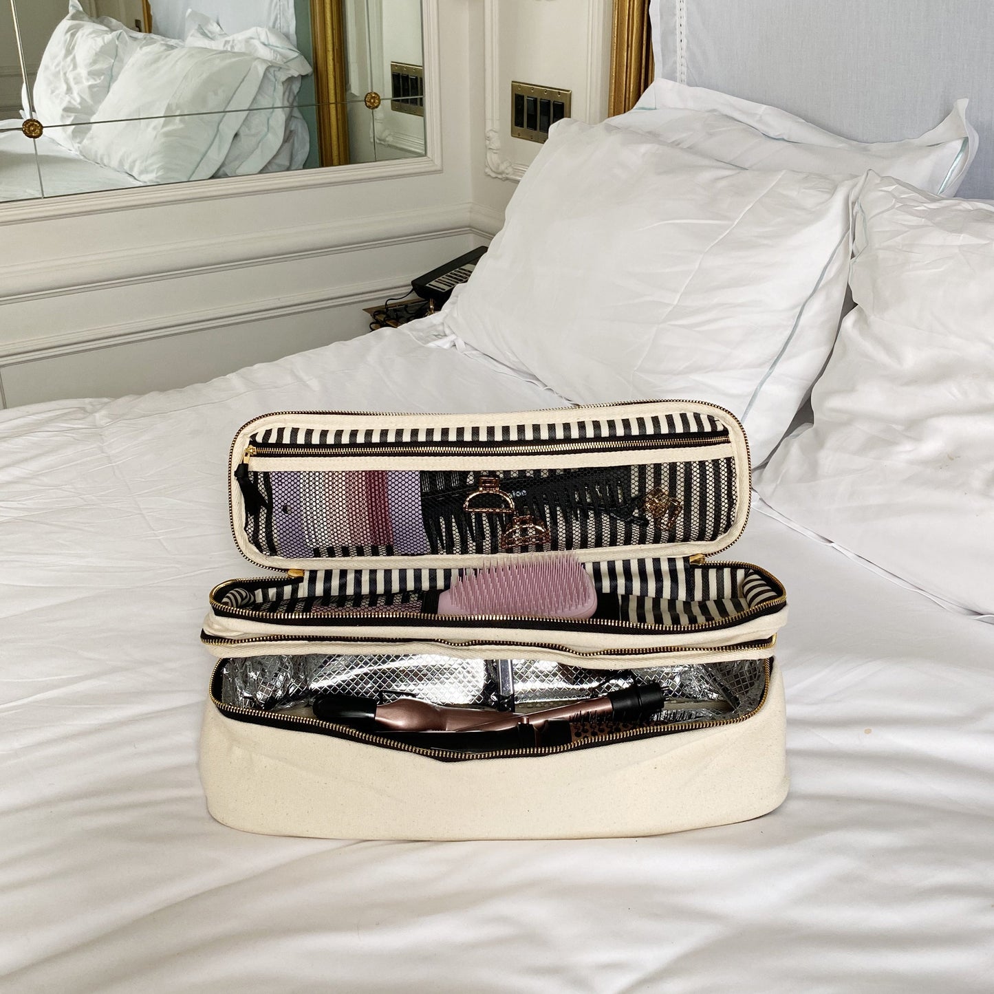 Bag-all cream 3-pack laundry and beauty case gift set open on bed with striped interior and travel essentials inside