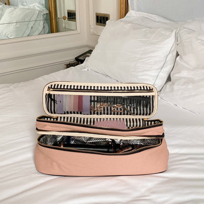 Pink blush Bag-all travel organizers and hair tools set displayed open on a white bed for stylish storage and easy access