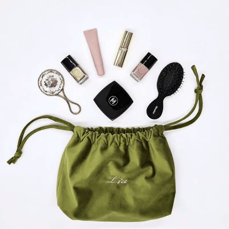 Green velvet drawstring makeup bag with personalized embroidery and essentials by Bag-all for easy organization and travel