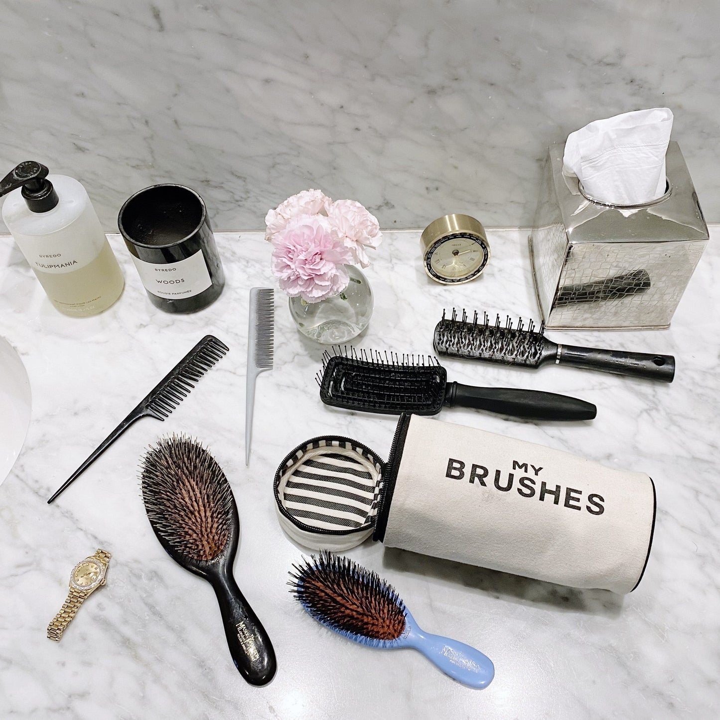 Bag-all cream Hair Ritual Deal gift set with 3 brushes and hair tools organizer on marble countertop with flowers and clock
