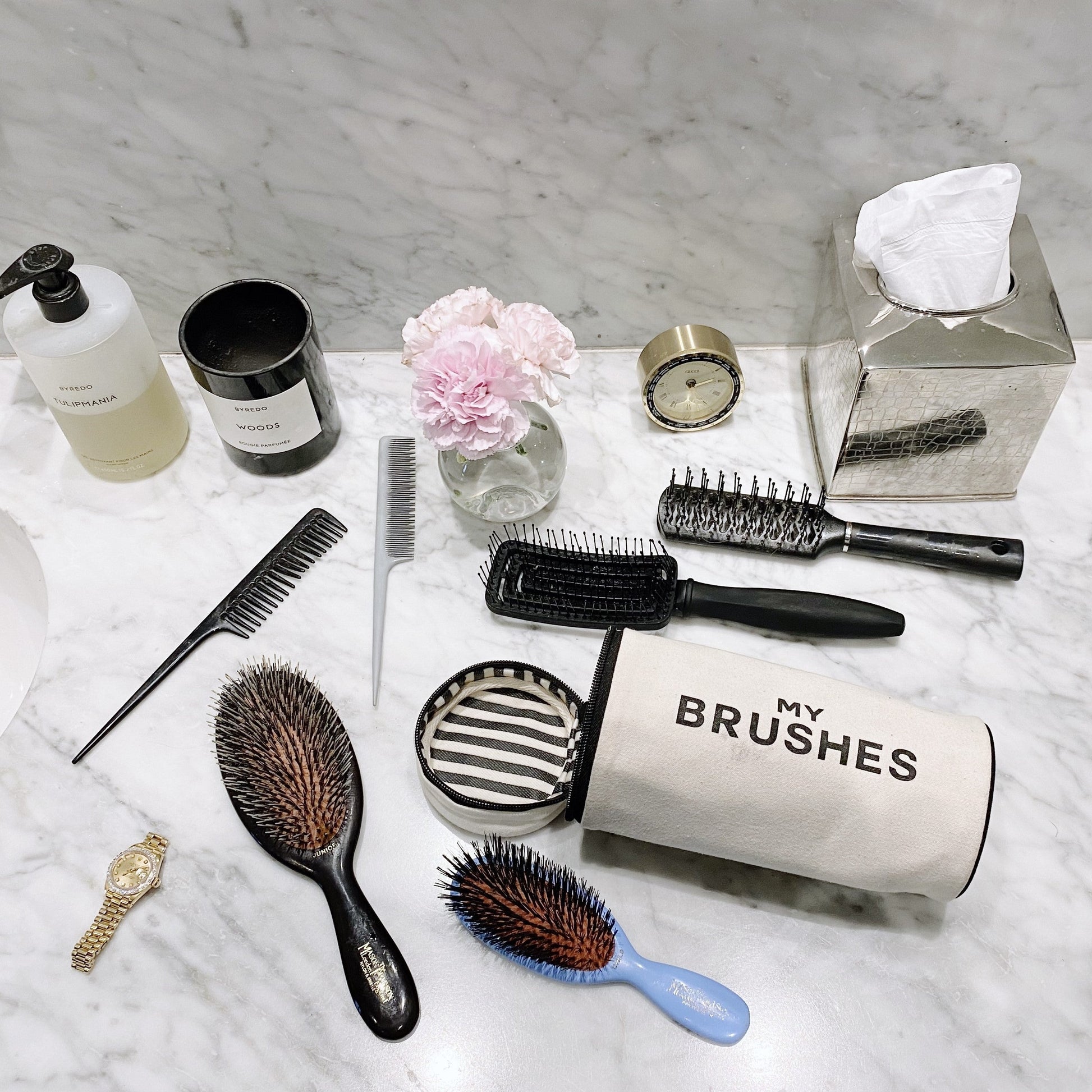 Bag-all cream Hair Ritual Deal gift set with 3 brushes and hair tools organizer on marble countertop with flowers and clock