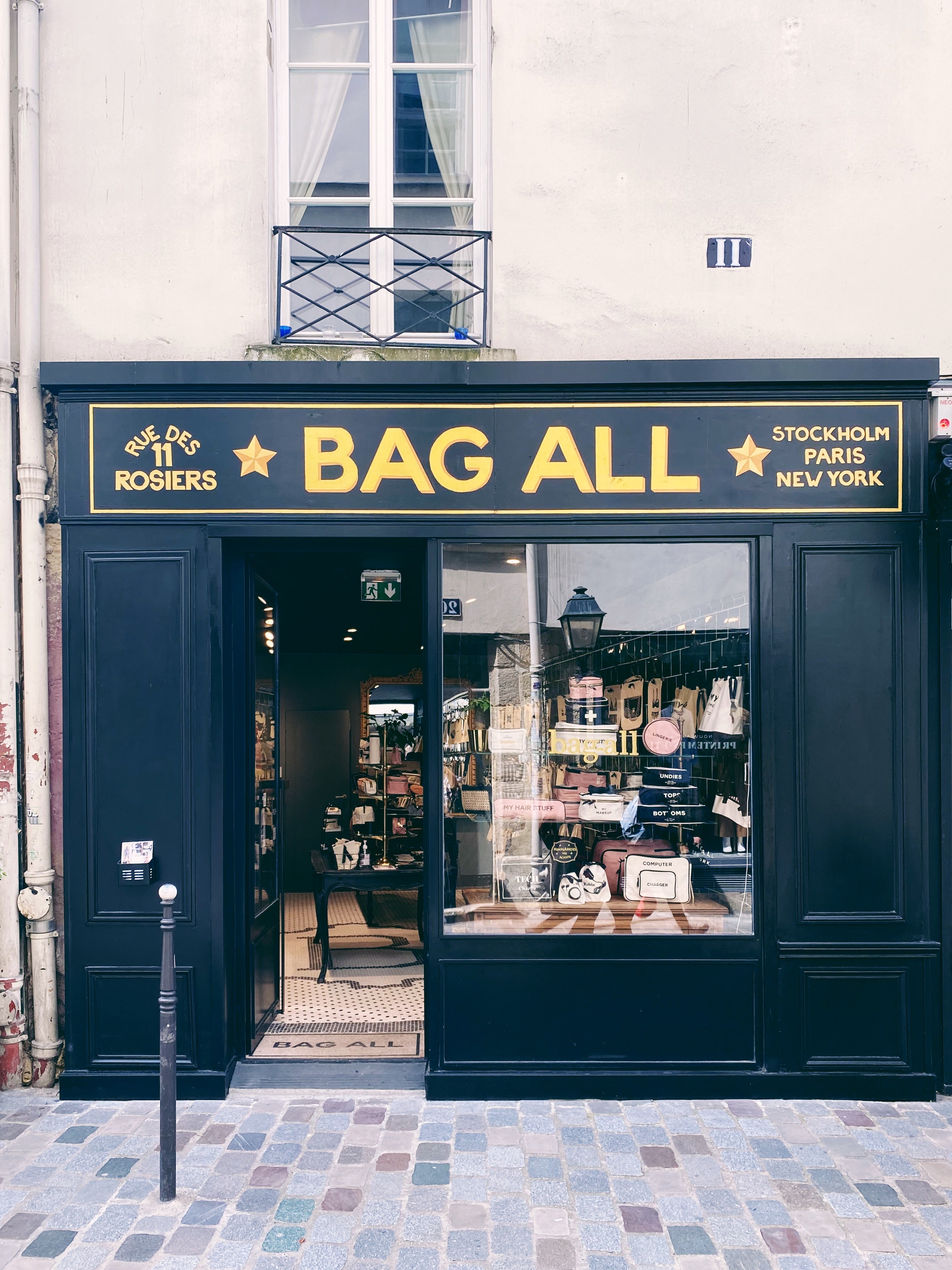 Bag-all boutique exterior with black and gold signage showing city names and window display gallery position 1