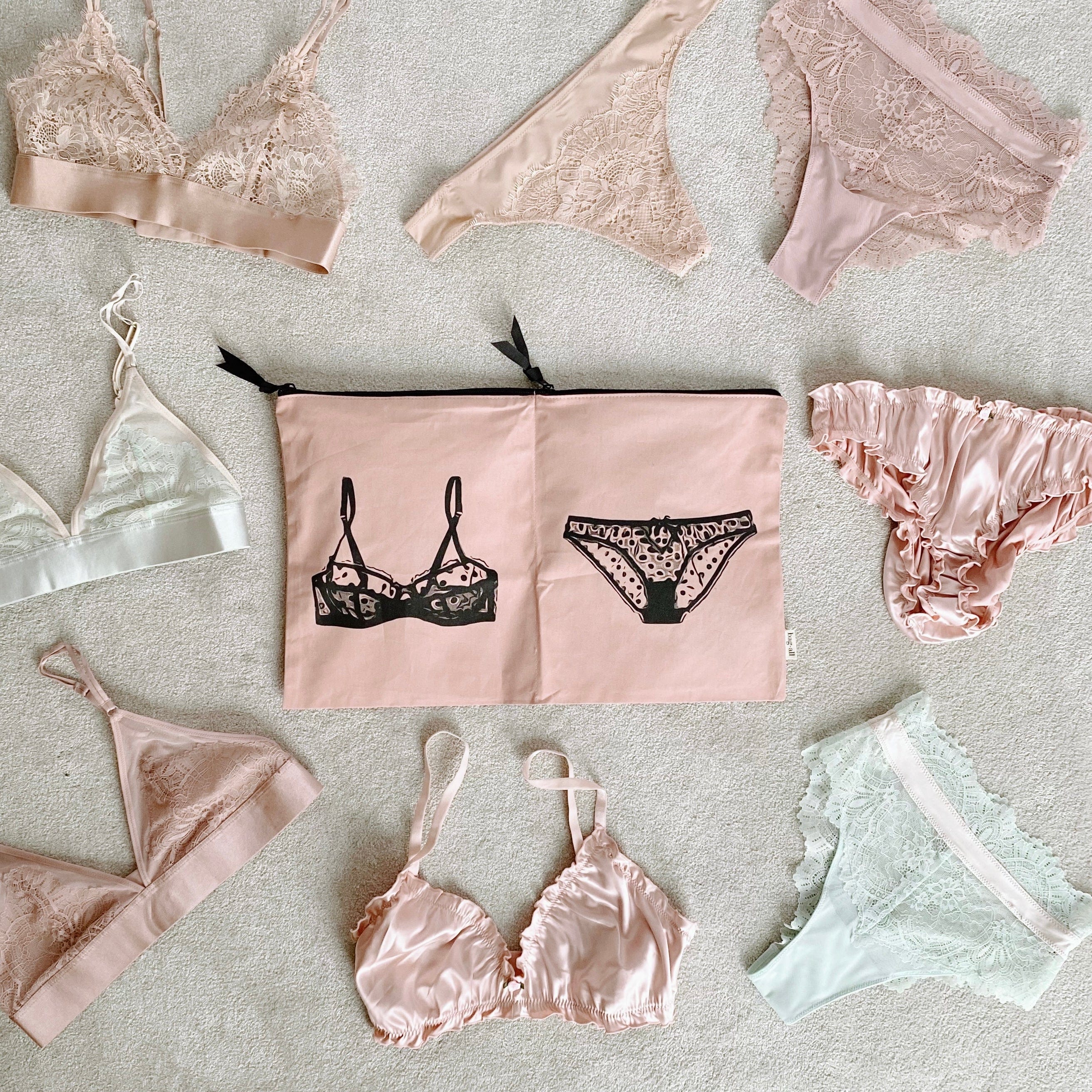 Bag-all Travel Glam 4-Pack featuring pink lingerie organizer pouch with black bra and panty design, surrounded by delicate lace undergarments in blush and ivory tones