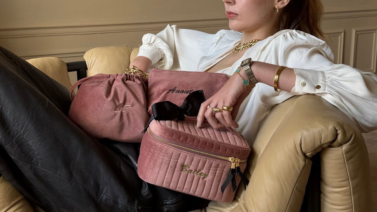 Bag-all pink quilted travel bags held by a woman seated in an armchair, showcasing stylish travel organization for frequent travelers