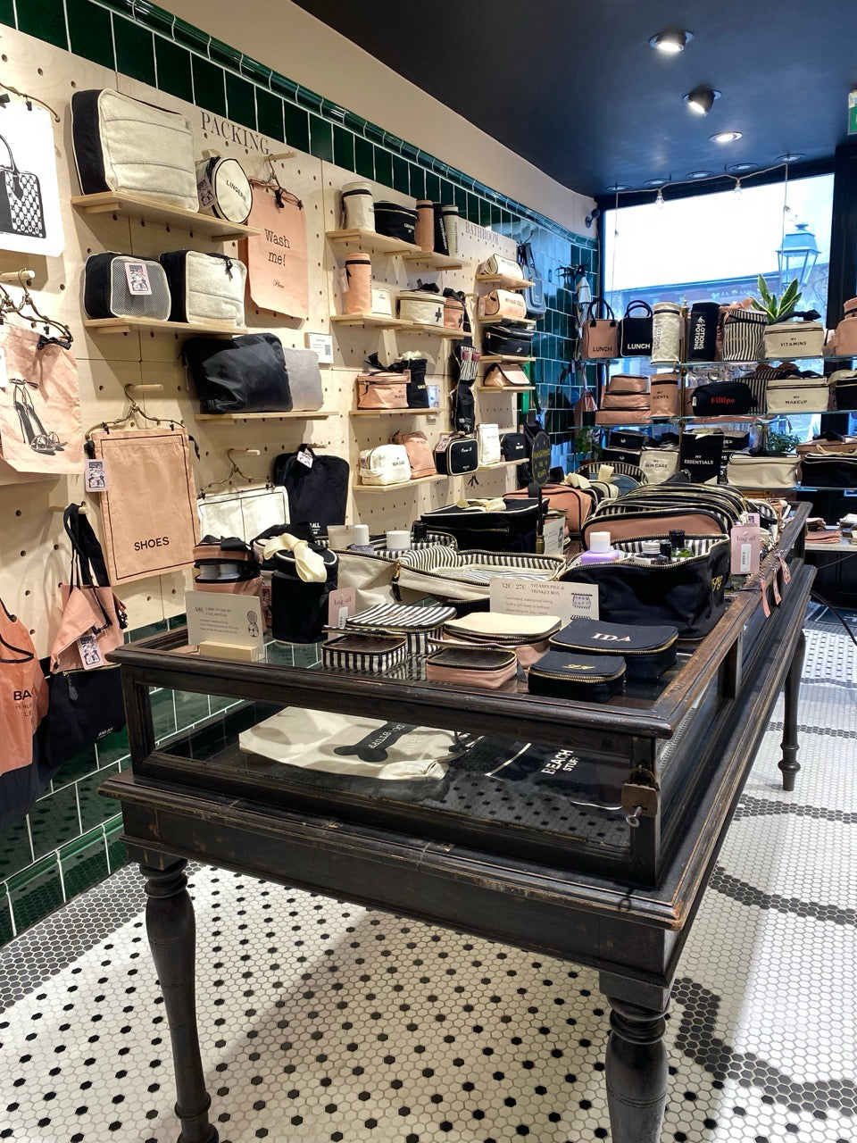 Bag-all bags and organizers displayed on vintage table and shelves inside store with green tiled wall gallery position 1