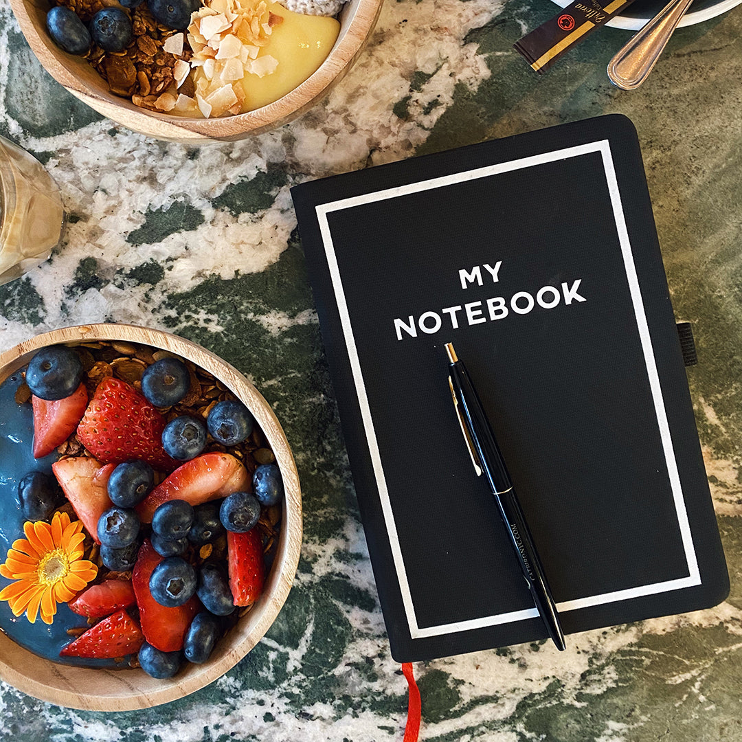 Bag-all My Notebook with sleek black cover and pen, styled with fresh berries and granola bowls on marble surface - perfect for creative journaling and mindful planning