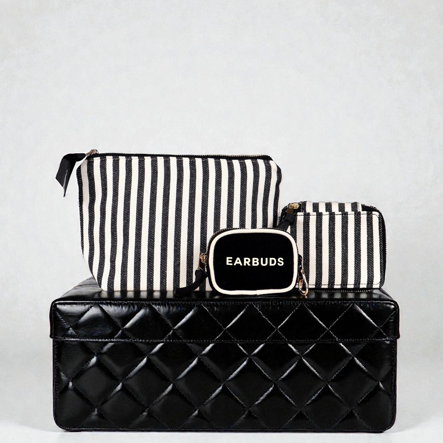 Bag-all striped Handbag Organizer Trio with trinket, makeup, and earbud cases on black quilted box background