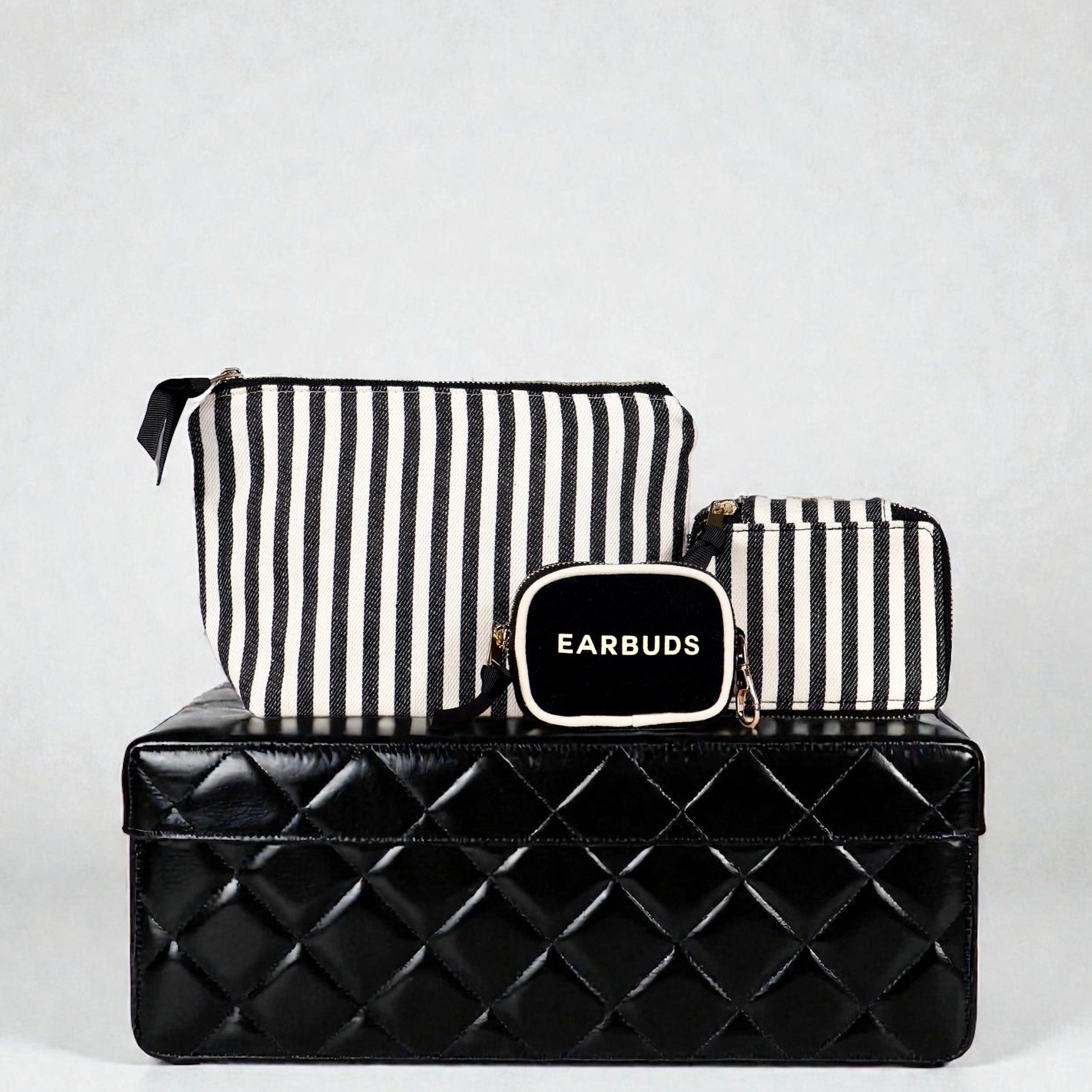 Bag-all striped Handbag Organizer Trio with trinket, makeup, and earbud cases on black quilted box background