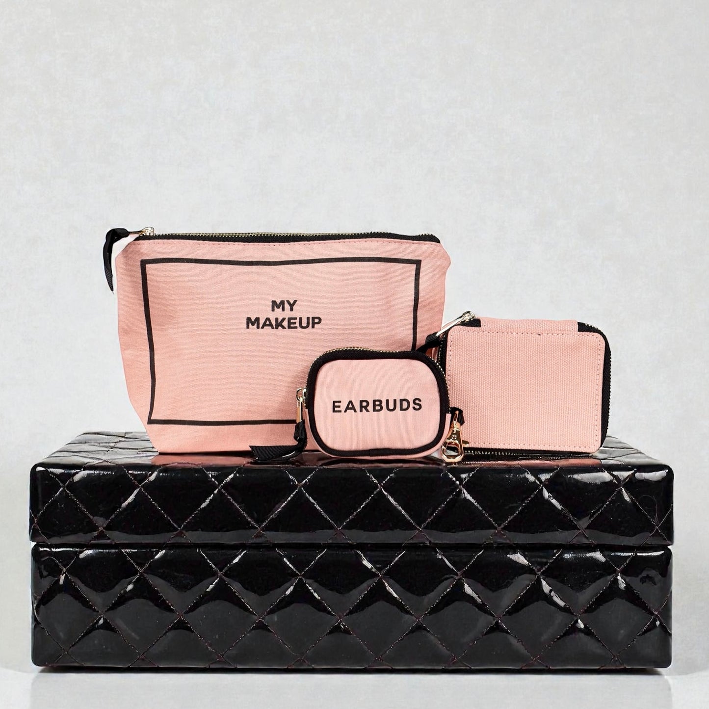 Three pink Bag-all cotton organizers labeled My Makeup, Earbuds, and card case on black glossy box