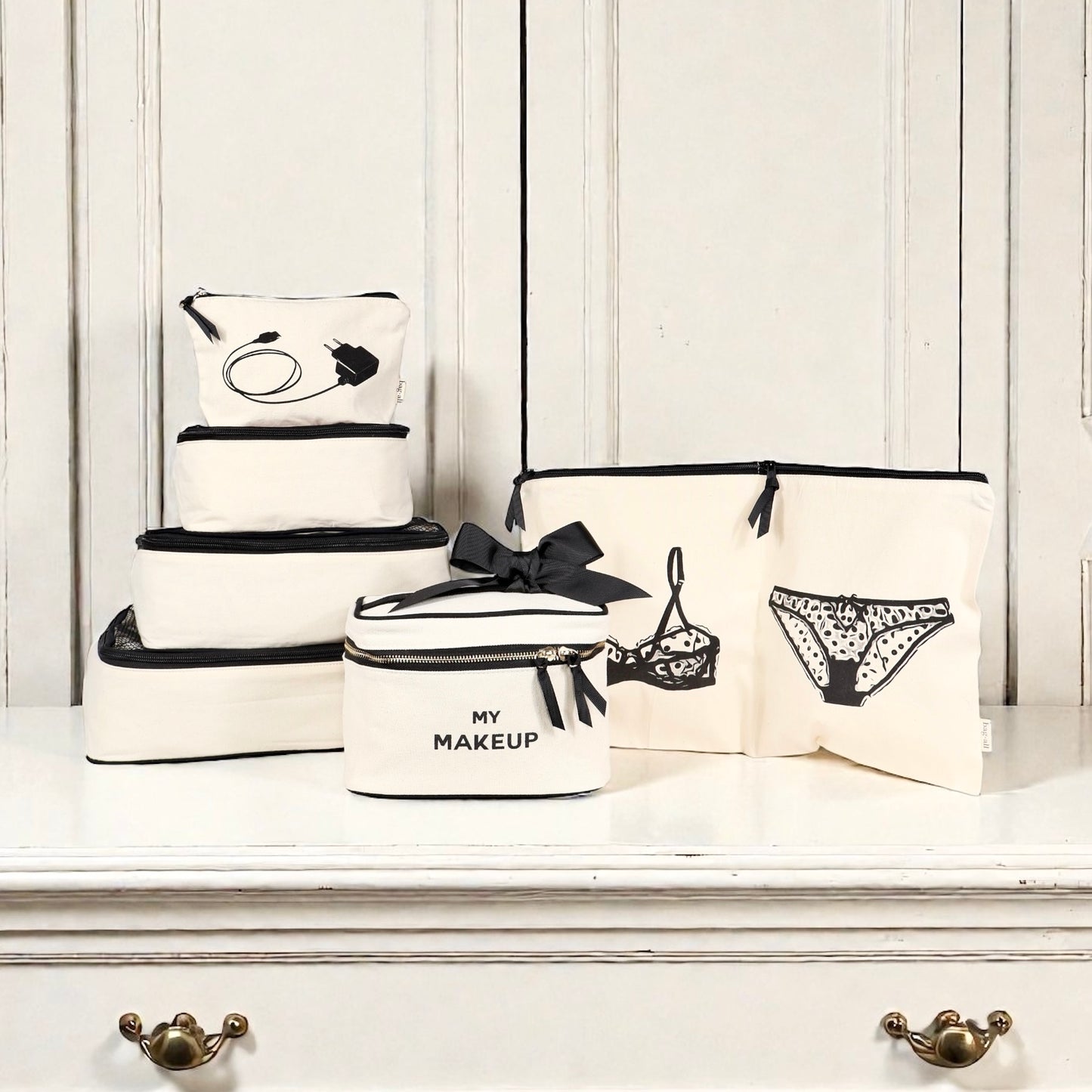 Set of natural cotton Bag-all travel organizers with black trim including lingerie, makeup, tech, and cream pouches