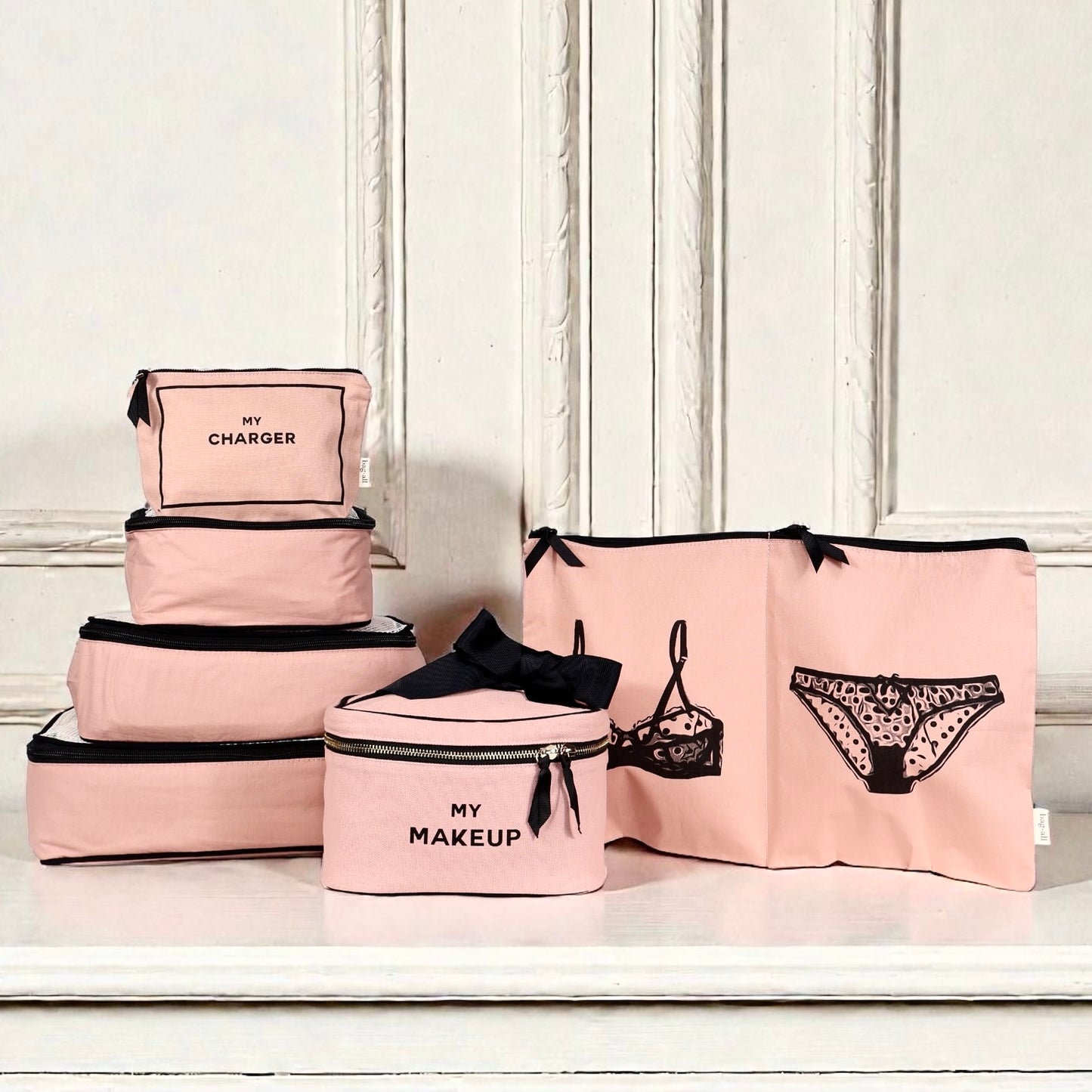 Pink Bag-all Travel Glam 4-Pack with organizer cubes, makeup bag, and lingerie pouches on white surface