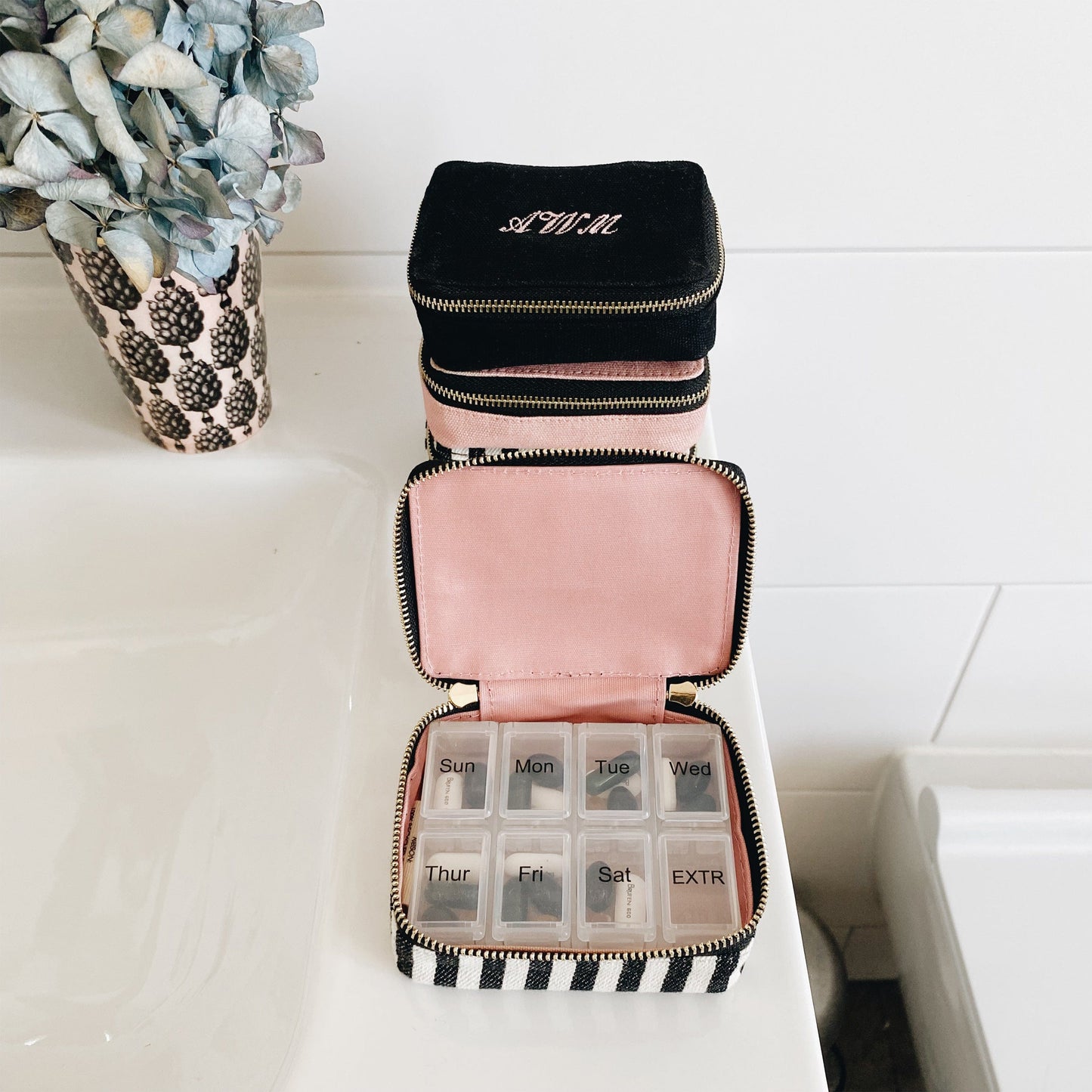 Bag-all Pill Organizing Case with Weekly Pill Organizer featuring black exterior, pink interior, striped pattern, and 8-compartment weekly organizer. Monogrammable cotton case with secure zipper closure.